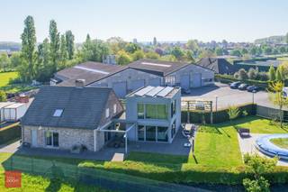 Nijverheidsgebouwen met private toegangsweg en alleenstaande woning (263m² vloeroppervlakte met inkomhall, living met zitruimte, ingerichte keuken, 5 slaapkamers, 2 badkamers, dressingkamer, wasplaats, berging. Laatste verbouwing 2009. Airco en screens, deels vloerverwarming). Industriegebouwen 2 x 660m² met sectionale poorten, burelen, kitchenette, kleedruimte en refter (bouwjaar 1994)