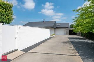 Afgeschermd van straatbeeld en met toegangsdreef bereikbaar. Ruime tijdloos hernieuwde villa (462m² vloeroppervlakte) bestaande uit een inkomhall, living met open haard, ingerichte keuken (Fraeye), eetruimte, annex berging met toegang tot mooie kelder en zolder, 3 slaapkamers (1 beneden), badkamer en bureel op verdieping. Aangesloten uitbouw met hoofdslaapkamer / dressing, / badkamer, leefruimte met open haard, sauna, ontspanningsruimte, technische ruimte. Garage voor 2 wagens, carport met tuinberging en parking. Zwembad (Bob Monteyne) met buitendouche. Alle modern comfort (vloerverwarming, 59m² zonnepanelen met groenestroomcertificaten tot 2032, 20.000 l regenwater etc)