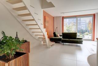 Unieke en rustgevende nieuwbouwwoning in het hart van Boechout<br /><br />Bent u op zoek naar een instapklare, energiezuinige nieuwbouwwoning op een rustige en groene locatie, maar toch op wandelafstand van winkels, scholen, openbaar vervoer en andere voorzieningen? Dan is deze prachtige halfopen nieuwbouwwoning in Boechout zeker het ontdekken waard.<br /><br />Oppervlakte bewoonbare woning =€ 140 m2, 3 terrassen= 26 m2<br />Oppervlakte tuin = 132 m2<br />Oriëntatie tuin = ZW<br />Project: Midden -Jan Cockxplein 7 te 2530 Boechout<br />Staat: nieuwbouw 2025 -2026 Halfopen<br />Voorlopige oplevering: 15 juni 2026<br /><br />Indeling:<br />Gelijkvloers: <br />* Hall: ingemaakte kasten + elektriciteitsberging + toilet met handwasser<br />* Woonkamer + volledig ingerichte open keuken - open trap naar verdiep 1<br />* Zuidterras keramische tegels met verlichting/stopcontact en 2 kraantjes (stads-en regenwater)<br />* aangelegde onderhoudsarme tuin - super geïsoleerd tuinhuis (6 m2), gebeitst- verlichting, schakelaar en stopcontact + omheining met hek dat doorgang biedt naar park<br />* Hoogwaardige inrichting: volhouten shutters, elektrische screens, elektrische zonneluifel, vliegenramen (cassettehor zuidterras)<br />* Keukenberging: warmwaterboiler -<br />* Eigen regenwaterput met recuperatie-systeem, fijnfilters, en automatische overschakeling naar stadswater <br />* Afzonderlijke septische put<br />* ventilatiesysteem D<br />* Lucht-water warmtepomp met vloerverwarming en koeling E-peil 16<br />* Dubbel isolerende beglazing HR<br />* Volledig geschilderd<br />* op elk verdiep accespoints .<br />Verdiep 1:<br />* Slaapkamer 1: (18 m2) met ingemaakte wandkast/draai-kiepramen<br />* Wasberging: wasmachine/ droogkast - met warmtepompsysteem<br />* Hall: Afzonderlijk toilet met handwasser<br />* Badkamer: dubbele lavabo, instapdouche + handdoekdroger/ Draai-en kiepraam met shutters en hor<br />* Slaapkamer 2 (Muziekstudio) : 17m2 -extra stopcontacten/Draai-en kiepramen met shutters en elektrische screens + horren<br />* Overal extra stopcontacten voorzien<br />Verdiep 2: <br />* studio/ polyvalente ruimte : 26.80m2 met zuid-en noord/oostterras (groenterras NO) -verlichting, stopcontact, kraantje regenwater<br />* Afzonderlijke toiletruimte met lavabo en open kastgedeelte<br />* Open nis met legplanken en bergingsruimte <br />* 2 dubbele ramen met vliegendeur (cassette) en elektrische screens + shutters<br />* Slaapzetel: uitklapbaar 140 cm br x 200 l<br />* Tv aansluiting, accespoints<br />Voordelen: <br />* geen syndicuskosten<br />* Geen onderhoud voor gemeentepark