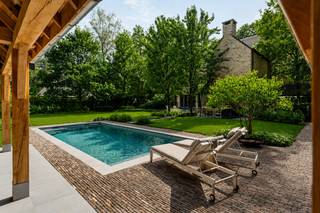 Welkom in deze uitzonderlijke villa, gelegen in een rustige en residentiële dreef in één van de meest gegeerde woonomgevingen van Heide-Kalmthout. Omringd door statige villa's op ruime percelen en volwassen bomen geniet u hier van absolute rust, privacy en een unieke woonkwaliteit.<br /><br />Ondanks de groene ligging bevinden de centra van Heide en Kapellenbos, scholen, winkels en openbaar vervoer zich op korte afstand. Dankzij de nabijheid van meerdere treinstations en de vlotte verbinding richting Antwerpen (en de haven) en Nederland combineert deze locatie moeiteloos exclusief wonen met een uitstekende bereikbaarheid. Ook natuurliefhebbers komen hier volledig aan hun trekken, met de Kalmthoutse Heide en de Golf van Kapellen vlakbij.<br /><br />Indeling van de villa:<br />Via de imposante inkomhal met open vide, vestiaire en gastentoilet wordt u verwelkomd in een woning waar ruimte, licht en luxe centraal staan.<br />De royale leefruimte bestaat uit een sfeervol salon met open haard en een aparte tv-kamer. De exclusieve leefkeuken vormt het hart van de woning en is afgewerkt met een indrukwekkend kookeiland, een La Cornue gasfornuis, hoogwaardige natuursteen en alle denkbare toestellen. Een droom voor menig hobbykok. Aansluitend bevindt zich een stijlvolle eetkamer met haard. Vanuit vrijwel elke leefruimte geniet u van een prachtig zicht op de tuin en heeft u directe toegang tot de terrassen.<br /><br />Eerste verdieping:<br />Via een stijlvolle trap bereiken we de eerste verdieping, waar zich een volledig afsluitbare mastervleugel bevindt met een ruime slaapkamer, luxueuze ensuite dressing en een luxe badkamer met ligbad, inloopdouche, dubbele wastafel en toilet. Daarnaast zijn er nog twee ruime slaapkamers, waarvan één met dressing en de andere ingericht als hobbykamer. De tweede badkamer is even luxueus ingericht met dubbele douche, ligbad en badkamermeubel. Op deze verdieping bevindt zich een super handige wasruimte en een nachttoilet.<br /><br />Tweede verdieping:<br />De trap zet zich voort naar de overloop van deze verdieping en beschikt over nog eens drie ruime slaapkamers, waarvan twee voorzien zijn van nieuwe maatwerkkasten. Een derde badkamer is eveneens uitgerust met ligbad, badkamermeubel en toilet.<br /><br />Buitenruimte:<br />De volledig nieuw aangelegde tuin ademt exclusiviteit. Hier geniet u van een verwarmd zwembad waarvan de geautomatiseerde filterinstallatie recent werd vernieuwd, een nieuwe luxueus uitgeruste poolhouse met buitenbar, kleedkamer, toilet en buitendouche. Dankzij de putboring en automatische irrigatie blijft de tuin het hele jaar door perfect onderhouden. Genieten van rust en de tuin kan u op één van de terrassen.<br /><br />Parkeren:<br />De woning beschikt over een ruime dubbele garage met automatische poorten, voorzieningen voor een laadpunt, een zij-ingang en een vernieuwde oprit met parkeergelegenheid voor meerdere wagens. Buiten het perceel is er nog parkeergelegenheid voor de gasten.<br /><br />Troeven van de villa:<br />•Exclusieve villa in tijdloze Cotswold-architectuur <br />•Volledig gerenoveerd en gemoderniseerd (2019 & 2024) <br />•Verwarmd zwembad met nieuwe filterinstallatie en luxueuze poolhouse <br />•Exclusieve leefkeuken met La Cornue-fornuis <br />•Zes ruime slaapkamers en drie complete badkamers<br />•Afsluitbare mastervleugel met dressing en ensuite badkamer <br />•Zonnepanelen, waterverzachter en putboring <br />•Energiezuinig B-label <br />•Absolute privacy op een residentiële toplocatie <br /><br />Kortom:<br />Deze villa is een unieke opportuniteit voor wie op zoek is naar een luxueuze gezinswoning waar architectuur, comfort en natuur naadloos samensmelten. Elk detail werd met oog voor kwaliteit afgewerkt, waardoor u hier zonder zorgen kan genieten van exclusief wonen in één van de mooiste lanen van Heide-Kalmthout.<br /><br />Overtuig uzelf van deze unieke buitenkans tijdens een bezoek ter plaatse.
