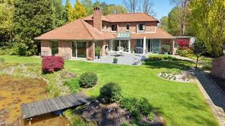 Zeer rustig en uitzonderlijk gelegen villa op een achterliggend perceel van 30 are 48 ca met private toegangsweg, grote vijver en zeer mooie aangelegde tuin.<br />De eigendom paalt met de achterkant aan groene omgeving. <br />Zuid-west georiënteerd.<br />Omvat: inkomhal, wc, zeer ruime zonnige living met mezzanine-bureel-tv-hoek en inbouwhaard, volledig ingerichte keuken met eethoek, koele berging, garage + carport, 3 bad-of douchekamers, 4 slaapkamers (waarvan 2 slaapkamers en 1 badkamer op gelijkvloers), dressing. Bijgebouw: homeoffice en tuinberging.<br />Perfecte staat en instapklaar. <br />Bouwjaar 1991 en vernieuwingswerken oa: keuken en badkamer in 2008 - tuinaanleg en terras 2020 - dakgoten en dakbehandeling 2022 - schilderen buitenschrijnwerkerij 2023.<br />De elektrische installatie is conform voor de komende 25 jaar.<br />CV met mazout - vloerwarming. EPC 237 kwh/m² - energielabel C - UC3819792RES1. Ki 3.725 euro.<br />Totale vloeroppervlakte: 345m² + tuinberging. <br />De villa is asbestveilig volgens het asbestinventarisattest. <br />Stedenbouwkundige vastgoedinfo: vergunning uitgereikt - woonpark = residentieel woongebied - verkavelingsvergunning - geen voorkooprecht ruimtelijke ordening - geen rechterlijke herstelmaatregel of bestuurlijke maatregel opgelegd.<br />Niet overstromingsgevoelig - gebouwscore A - perceelscore A (bevestigd met actualisatie door deskundige).