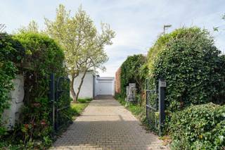 <em>Deze woning in Sint-Truiden is een uitzonderlijk voorbeeld van een kunstenaarswoning waarin architectuur, beeldende kunst en landschap in volledige symbiose samenkomen. Ontworpen in 1961 door architect Adolf Nivelle, in nauwe dialoog met de toenmalige bouwheer en kunstenaar Toon Vanmechelen, overstijgt deze woning het louter functionele wonen. Het is een plek waar denken, maken en leven samenkomen in één coherent geheel, gedragen door een sterke modernistische visie met uitgesproken brutalistische accenten.</em><br /><br /><strong>De signatuur van adolf nivelle</strong><br />Adolf Nivelle behoort tot een generatie architecten die zich bewust afzette tegen ornament en oppervlakkigheid, en resoluut koos voor een architectuur van essentie en structuur. Zijn werk wordt gekenmerkt door een helder constructief denken, een consequente materialiteit en een bijzondere gevoeligheid voor ruimte, licht en inplanting. In deze woning komt die visie tot volle maturiteit.<br />Nivelle benadert architectuur als een totaalkunstwerk waarin elk element — van dragende structuur tot detailafwerking — deel uitmaakt van een groter geheel. De strakke geometrie, de ritmiek van horizontale lijnen en de zorgvuldige positionering op het perceel tonen een architect die niet enkel bouwt, maar componeert. De woning is geen object op zich, maar een ruimtelijke ervaring die zich ontvouwt in relatie tot haar omgeving.<br /><br /><strong>De kunstenaar als medeschepper</strong><br />De aanwezigheid van kunstenaar Toon Vanmechelen als bouwheer en mededenker geeft deze woning een extra gelaagdheid. Dit is geen klassieke samenwerking waarbij kunst pas nadien wordt toegevoegd, maar een intrinsieke verweving van kunst en architectuur vanaf de eerste schets. De woning werd opgevat als een leef- en werkplek waarin artistieke expressie een vanzelfsprekende plaats krijgt.<br />De beeldhouwwerken en artistieke ingrepen, zowel in de tuin als in de overgangszones van de woning, functioneren niet als decoratie maar als ruimtelijke ankerpunten. Ze begeleiden de beweging doorheen het huis, creëren accenten en versterken de beleving van schaal en perspectief. De patio en voortuin worden zo verlengstukken van het atelier, terwijl het interieur een subtiele galerie wordt waarin kunst en dagelijks leven elkaar ontmoeten.<br /><br /><strong>Architectuur, kunst en tuin in dialoog</strong><br />Wat deze woning bijzonder maakt, is de continue dialoog tussen de rationele helderheid van de architectuur, de expressieve kracht van de kunst en de verstilde aanwezigheid van de tuin. Waar Nivelle structuur, rust en orde brengt, voegt Vanmechelen een meer intuïtieve, sculpturale laag toe. De tuin vormt daarin geen decor, maar een wezenlijk onderdeel van de woonbeleving.<br /><br />Met grote zorg werd het domein aangelegd en onderhouden, niet volgens een strak Frans schema, noch volgens een uitgesproken Engelse traditie, maar veeleer vanuit het gevoel en de intuïtie van de eigenaar. Die persoonlijke benadering geeft de buitenruimte een bijzondere zachtheid en vanzelfsprekendheid. De bloei begint vroeg in het seizoen met de magnolia, waarna de tuin zich verder ontvouwt in een bijna continue opeenvolging van kleuren, texturen en geuren. Doorheen het jaar blijft zij in beweging, levendig en toch sereen.<br /><br />Eens op het domein komt men in een oase van rust terecht, waarin de tuin een hoofdrol speelt. Grote glaspartijen kaderen zichten op het groen en op de aanwezige sculpturen, waardoor binnen en buiten, kunst en natuur, voortdurend met elkaar verweven blijven. De tuin verzacht de kracht van de architectuur, zonder haar te verzwakken, en versterkt tegelijk het contemplatieve karakter van de woning.<br /><br /><strong>Een leefomgeving voor makers</strong><br />De indeling en ruimtelijke opbouw van de woning verraden haar oorsprong als kunstenaarswoning. Naast de genereuze leefruimtes en slaapkamers is er expliciet ruimte voorzien voor creatie, reflectie en experiment. De aanwezigheid van een atelier en de flexibele invulling van verschillende ruimtes maken het geheel bijzonder geschikt voor wie wonen en werken wil combineren.<br />Tegelijk blijft de woning in haar opzet bijzonder helder en functioneel. De circulatie is logisch, de ruimtes zijn goed geproportioneerd en het daglicht wordt op een doordachte manier doorheen het huis geleid. Dit zorgt voor een leefkwaliteit die, ondanks de uitgesproken architecturale identiteit, bijzonder comfortabel en vanzelfsprekend aanvoelt.<br /><br /><strong>Een erfstuk met toekomst</strong><br />Hoewel de woning vandaag een energetische update vraagt, blijft de architecturale basis uitzonderlijk waardevol. De robuuste structuur en de sterke ontwerpvisie bieden een solide kader voor een hedendaagse interpretatie, waarbij duurzaamheid en comfort kunnen worden geïntegreerd zonder het karakter aan te tasten.<br /><br />Deze woning is meer dan een plek om te wonen. Het is een erfstuk waarin architectuur, kunst en landschap elkaar versterken — een omgeving die inspireert, vertraagt en verdiept. Een zeldzame kans voor wie op zoek is naar een woning met een verhaal, een ziel en een uitgesproken identiteit.<br /><br /><strong>Meer ontdekken?</strong><br />Wil je graag thuiskomen in deze uitzonderlijke woning?<br />Contacteer mij dan snel voor meer info of een persoonlijk bezoek ter plaatse!<br /><br /><em>De vermelde oppervlaktes zijn slechts indicatief. Katrien Wouters - creating IMMOtions kan niet verantwoordelijk gesteld worden voor de juistheid van de aan haar verstrekte gegevens.  </em>