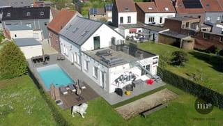 IMMO STORE biedt u deze sinds 2015 VOLLEDIG GERENOVEERDE, ENERGIEZUINIGE woning aan, VERNIEUWD met oog voor COMFORT en FUNCTIONALITEIT. Dankzij de ROYALE bewoonbare oppervlakte, de LICHTRIJKE leefruimtes en de DOORDACHTE indeling is dit de ideale thuis voor GROTE GEZINNEN, ZELFSTANDIGEN, THUISWERKERS of wie op zoek is naar extra ruimte.<br />Via de inkomhal betreedt u de gezellige zithoek en aparte TV-corner. De woonkamer geniet van een overvloed aan NATUURLIJK licht en sluit naadloos aan op de VOLLEDIG INGERICHTE keuken. Verder beschikt de woning over een leuke speelruimte voor de kinderen en een praktische, ruime berging.<br />Op de eerste verdieping bevinden zich een PROFESSIONEEL bureau, DRIE volwaardige slaapkamers en <br />TWEE badkamers met apart toilet. De zolderverdieping werd OPTIMAAL benut en omvat nog eens DRIE EXTRA slaapkamers en een bijkomende gastenkamer.<br /><br />Het ruime bijgebouw van 250 m², uitgerust met TWEE hoge automatische poorten, biedt tal van mogelijkheden en kan volledig naar eigen wens worden ingericht als opslagruimte, toonzaal, atelier, garage of hobbyruimte. Onder het dak van dit bijgebouw bevindt zich bovendien een gezellig volwaardig APPARTEMENT van 80 m². Deze splinternieuwe, volledig uitgeruste extra woonunit combineert modern comfort met een hoogwaardige afwerking en geniet van alle hedendaagse voorzieningen.<br /><br />Buiten geniet u van een groot ZUIDGERICHT TERRAS met een prachtig zicht op de ZONOVERGOTEN TUIN en het VERWARMD ZWEMBAD — dé perfecte plek om in alle rust te ontspannen en volop van het buitenleven te genieten. Is dit iets voor u? Aarzel dan niet, contacteer IMMO STORE op 02/203 03 03 en ontdek het POTENTIEEL van dit MULTIFUNCTIONELE gebouw +++ ELEKTRICITEIT CONFORM +++ ZONNEPANELEN +++ EPC 'B' +++ WARMTEPOMP voor ZWEMBAD +++