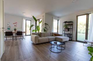 <div><div> <p>Gelijkvloers nieuwbouwappartement met tuin en autostaanplaats.</p><p>Ruim en hoogwaardig afgewerkt nieuwbouwappartement van 104 m², gelegen op de gelijkvloerse verdieping en voorzien van een aangelegde tuin en terras. Het appartement beschikt over een inkomhal met gastentoilet, een ruime leefruimte met open keuken en grote raampartijen die zorgen voor een aangename lichtinval. De volledig ingerichte keuken is voorzien van alle nodige toestellen. Verder beschikt het appartement over twee slaapkamers, waarvan één met een aparte dressingkamer. De badkamer is uitgerust met een ligbad en een dubbele wastafel. Inclusief ondergrondse autostaanplaats en kelderberging. Algemene onkosten: € 70/maand. Een ruim en instapklaar nieuwbouwappartement met tuin, terras en ondergrondse autostaanplaats.</p></div> </div>