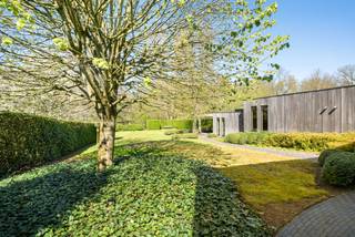 Deze bijzondere gelijkvloerse villa combineert hedendaags comfort met een prachtige natuurlijke omgeving. Deze eigendom wordt gekenmerkt door grote glaspartijen, een hoogwaardige afwerking en een unieke architectuur.<br />Door het achterliggende natuurgebied, dat rechtstreeks via de tuin toegankelijk is, is het zowel binnen als buiten heerlijk vertoeven.<br /><br />Deze woning is volledig gelijkvloers voorzien waardoor het een ideale gezinswoning is maar ook uitermate geschikt voor kopers op leeftijd of mindervaliden.<br />De eigendom bestaat uit een lichtrijke woonkamer, half open keuken, 2 slaapkamers die omgevormd kunnen worden naar 3 slaapkamers, ruime badkamer, dressing, apart toilet, bergruimte, wasplaats, technische ruimte, aparte garage en multifunctioneel bijgebouw met overdekt terras.<br /><br />Indeling:<br />U betreedt de woning via een ruime inkomhal die voorzien is van een apart toilet en praktische bergruimte. De ruime en gezellige leefruimte met grote glaspartijen en een sfeervolle pelletkachel vloeit naadloos over in de recent vernieuwde, volledig uitgeruste keuken met uitzicht op de tuin.<br />Oorspronkelijk beschikte de woning over drie slaapkamers, waarvan er momenteel twee samengevoegd zijn tot een royale masterbedroom. Deze slaapkamer beschikt over een eigen dressing met op maat gemaakte kasten en een prachtige badkamer met ligbad, inloopdouche en hoogwaardig afgewerkt badkamermeubel.<br />Voorts bevindt er zich een praktische wasplaats/technische ruimte.<br /><br />Tuin:<br />De tuin biedt een oase van rust door zijn fraaie beplanting en uitzicht op het achterliggende natuurgebied. De tuin is volledig omheind en uitgerust met robotmaaier. Op het perceel bevindt er zich een aparte garage, alsook een multifunctioneel bijgebouw met kitchenette wat ideaal is als gastenverblijf of tuinbureau. Dit bijgebouw is bijkomstig voorzien van een overdekt terras waardoor het hier in ieder seizoen zalig vertoeven is.<br /><br />Bijzonderheden:<br />- Gelijkvloerse villa met rechtstreekse toegang tot natuurgebied<br />- Aparte geïsoleerde garage en multifunctioneel bijgebouw met kitchenette, airco en verwarming<br />- Ideale combinatie tussen het wonen aan de rand van de stad, vlakbij de fietsostrade met de rust van de natuur<br />- 2 slaapkamers mogelijk opnieuw om te bouwen naar 3 slaapkamers<br />- Hoogwaardige afwerking en zeer goed onderhouden eigendom <br />- Dak vernieuwd 4 jaar geleden<br />- Alarm