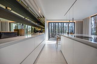 <p>Deze luxueuze villa is rustig gelegen in een doodlopende straat in het gegeerde Koningshof, op een boogscheut van het gezellige centrum van ’s-Gravenwezel, met scholen, sportclubs en openbaar vervoer vlakbij.</p>
<p>De woning is volledig georiënteerd naar de tuin en het fenomenale uitzicht op het omliggende groen, wat resulteert in een uitzonderlijk gevoel van rust, privacy en ruimte.</p>
<p><strong>INDELING GELIJKVLOERS:</strong></p>
<p>Bij het betreden van de villa komt u in een indrukwekkende inkomhal met hoge plafonds, ingebouwde vestiairekasten en een gastentoilet.</p>
<p>De riante leefkeuken vormt het hart van het huis en geniet van grote raampartijen die het buitengevoel naar binnen brengen en een naadloze connectie creëren met het terras en de tuin. De keuken is hoogwaardig afgewerkt met een Carrara marmeren werkblad, ingewerkte champagnekoeler en een centraal kookeiland met alle moderne comfort, waaronder een Bora kookplaat, Quooker-kraan en Miele toestellen. Aansluitend bevindt zich de eetruimte, waar u steeds geniet van het prachtige zicht op de tuin en het groen.</p>
<p>De lichtrijke leefruimte biedt een gezellige zithoek met gashaard, een stijlvolle bar en maatwerkkasten.</p>
<p>Verder beschikt het gelijkvloers over een praktische bureau met ingemaakte kasten, ideaal voor thuiswerk, en een polyvalente ruimte die kan dienen als speelkamer of extra kantoor.</p>
<p>Extra troeven zijn de bergkelder met kruipruimte onder het volledige gebouw en de ruime garage met dubbele poort. <br />Het zonnige terras sluit naadloos aan op de leefruimtes en vormt de perfecte plek om in alle rust te genieten van de tuin en het groene uitzicht.</p>
<p><strong>INDELING EERSTE VERDIEPING:</strong></p>
<p>Op de eerste verdieping bevindt zich een ruime overloop met visgraatparket en een praktische wasplaats.</p>
<p>De master suite van maar liefst 100 m²vormt een echte privé-oase met een slaapkamer, royale dressing en een luxueuze badkamer uitgerust met ligbad, dubbele douche en hoogwaardig kraanwerk. Het panoramisch uitzicht op de omliggende dennenbomen is ronduit indrukwekkend.</p>
<p>Daarnaast zijn er nog drie volwaardige slaapkamers van respectievelijk 22 m², 15 m² en 18 m², allen afgewerkt met maatwerk en ingemaakte kasten. De tweede badkamer beschikt over een inloopdouche, dubbele lavabo en toilet. Er is bovendien de mogelijkheid om een derde badkamer te voorzien.</p>
<p>Het geheel is afgewerkt met hoogwaardige materialen en uitgerust met de nieuwste technieken: zonnepanelen met thuisbatterij, geothermische warmtepomp, ventilatiesysteem type D, vloerverwarming (verwarmen en koelen), domotica, alarmsysteem en camerabewaking. Kortom, een uiterst energiezuinige en toekomstgerichte thuisbasis.</p>
<p><strong>BIJZONDERHEDEN:<br /></strong><br />- Gegeerde topligging in Koningshof<br />- Doodlopende straat<br />- Fenomenaal groen uitzicht<br />- High-end afwerking<br />- Zeer energiezuinig</p>