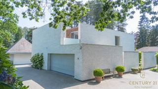 <h3>Exclusieve architectenvilla op toplocatie in villawijk De Lint</h3>
<p>Op een prachtig zuidwestgericht perceel, op wandelafstand van het unieke natuurgebied De Liereman, bevindt zich deze hedendaagse en onder architectuur gebouwde villa. Deze uitzonderlijke woning combineert tijdloze architectuur, royale leefruimtes en een hoogwaardig afwerkingsniveau met een uitstekende bereikbaarheid. Zowel Eindhoven als Antwerpen bevinden zich op slechts ca. 25 minuten rijden, waardoor u geniet van het beste van twee werelden: rust, natuur en een vlotte verbinding.</p>
<p>Bij aankomst wordt u verwelkomd in een ruime inkomhal met vestiaire en gastentoilet. Via stijlvolle dubbele deuren betreedt u de indrukwekkende woonkamer, waar de grote raampartijen een panoramisch zicht bieden op de prachtig aangelegde tuin. Het overvloedige natuurlijke licht en de fraaie tuinzichten creëren een unieke woonbeleving. Aansluitend bevindt zich een open ruimte die perfect dienst kan doen als bureau of leeshoek, open van karakter maar toch afzonderlijk van de leefruimte.</p>
<p>De sfeervolle doorkijkhaard vormt een elegante verbinding tussen de woonkamer en de royale leefkeuken. Deze keuken verkeert in perfecte staat van onderhoud, is uitgerust met kwalitatieve toestellen, beschikt over een groot werkblad en biedt plaats aan een ruime eettafel. Dankzij de grote schuiframen loopt binnen naadloos over in buiten. Achter de keuken bevinden zich een praktische bijkeuken en een aparte wasruimte. De inpandige dubbele garage met automatische poort en personenlift vervolledigt het comfort op het gelijkvloers.</p>
<p>Op de verdieping geeft de royale nachthal toegang tot de indrukwekkende master suite met inloopdressing en een luxueuze badkamer. Daarnaast zijn er nog twee volwaardige slaapkamers met een gedeelde badkamer. De ruime studiekamer kan eenvoudig worden ingericht als vierde slaapkamer en beschikt bovendien over een eigen terras.</p>
<p>Ook buiten weet deze villa te imponeren. De volgroeide, volledig omheinde tuin biedt optimale privacy en vormt een waar groen paradijs. Meerdere zonneterrassen en een overdekt terras nodigen uit om in alle seizoenen van het buitenleven te genieten. Het extra losstaande garagegebouw biedt bijkomende mogelijkheden voor wagenliefhebbers, hobbyruimte of extra opslag.</p>
<p>Naast het uitzonderlijke wooncomfort onderscheidt deze villa zich door haar onderhoudsvriendelijke karakter. Dankzij de duurzame aluminium raamprofielen en de kwalitatieve gevels in gevelsteen zijn er geen schilderwerken aan het buitenschrijnwerk of de buitenmuren nodig, wat resulteert in een stijlvolle uitstraling met een minimum aan onderhoud.<br /><br /><strong>Een uitzonderlijke villa voor wie ruimte, comfort, privacy, kwaliteit en een onderhoudsarme woonomgeving weet te waarderen.</strong></p>
<h3>Troeven van deze woning</h3>
<ul>
<li>Wandelafstand van natuurgebied De Liereman</li>
<li>Zuidwestgericht perceel met optimale bezonning</li>
<li>Personenlift naar de verdieping</li>
<li>Vloerverwarming op gelijkvloers én verdieping</li>
<li>Inpandige dubbele garage met automatische poort</li>
<li>Extra losstaand garagegebouw met bergzolder</li>
<li>Alarmsysteem</li>
<li>Zonnescreens</li>
<li>Fraai aangelegde, volledig omheinde tuin</li>
<li>Grote terrassen en overdekt, verwarmd terras</li>
</ul>