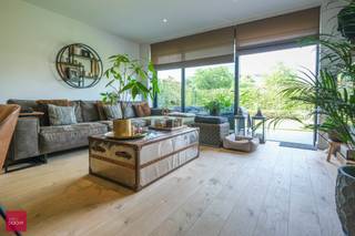 Inkomhal, living volledig in parket met open ingerichte keuken (Falcon fornuis), wasberging, terras vooraan met tuin, 2 slaapkamers met ingemaakte dressing, badkamer (bad + douche), toilet, terras achteraan met tuin,  parkingplaats en kelderberging. Zonnescreens aanwezig.