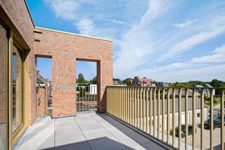 Deze triplexwoning heeft een aparte inkom aan de Stationsstraat en verrast met een moderne en innovatieve indeling. <br /><br />De leefruimte in loftstijl bevindt zich op de tweede verdieping en biedt een open en lichtrijke beleving, met een aansluitende leefkeuken en een extra grote berging. Hier bevindt zich ook een gastentoilet, wat het comfort compleet maakt. Het zuidgerichte terras is zijdelings afgeschermd voor optimale privacy.<br /><br />De woning beschikt over twee volwaardige slaapkamers: één op het gelijkvloers en één op de eerste verdieping. Beide slaapkamers zijn ruim genoeg voor een dubbel bed en een dressingkast en hebben elk een badkamer met dubbele wastafel, douche en toilet.<br /><br />Dankzij de flexibele indeling is deze woning geschikt voor een gezin, koppel, maar ook ideaal voor co-housing of eventueel iemand met een zelfstandige activiteit.<br /><br />Extra troef: een zeer ruime garage (aan te kopen voor €40.000,-), gelegen in de Ambachtsstraat. Deze biedt plaats aan een wagen, fietsen, afvalcontainers én heeft de mogelijkheid tot aansluiting van een laadpaal, rechtstreeks verbonden met de meterkast van de woning.<br /><br />*Vloerverwarming mét vloerkoeling, warmtepomp en zonnepanelen inbegrepen<br />*E-peil 10 (ver onder de norm), wat betekent: 5 jaar vrijstelling van onroerende voorheffing<br />*Mogelijkheid aankoop aan 6% BTW.