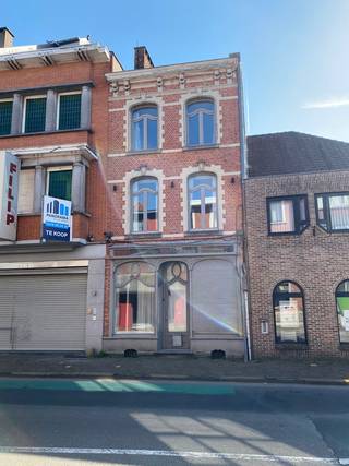 Bent u op zoek naar een woning met een uniek verhaal en eindeloze mogelijkheden? Dit solide pand uit 1957, gelegen in de levendige Bruggestraat, ademt karakter en biedt een zee aan ruimte. Waar vroeger de geur van verse broodjes de buurt verblijdde in de voormalige gelijkvloerse broodjeszaak, wacht nu een nieuwe toekomst.  Dit gebouw uit de late jaren 1950 combineert de stevige bouwkwaliteit van die tijd met een veelzijdige indeling. Het voormalige handelspunt op het gelijkvloers biedt een fantastische basis voor wie droomt van een ruim thuiskantoor, een atelier of simpelweg een riante extra leefruimte. De grote raampartijen aan de straatzijde zorgen voor een veellichtinval en een directe connectie met de omgeving.  Boven de voormalige handelsruimte bevindt zich het woongedeelte, waar de authentieke sfeer van de jaren '50 nog voelbaar is. Met zijn ruime vertrekken en logische opbouw is dit de ideale basis voor een renovatieproject dat modern comfort combineert met retro-charme.