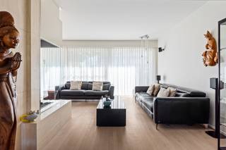 Een woning met een verhaal en uitzonderlijk veel ruimte. Deze karaktervolle eengezinswoning in naoorlogs modernistische stijl werd in 1970 ontworpen door architect <strong>Hubert Semal</strong> voor het echtpaar Celis, in samenwerking met beeldhouwer <strong>Albert Poels</strong>, bekend van de iconische Lange Wapper aan Het Steen. De uitgesproken architectuur, het gebruik van travertin, grote raampartijen en de verrassend doordachte indeling geven de woning tot vandaag een heel eigen karakter. Die eigenheid wordt mooi aangevuld door de ligging aan de Nieuwdreef: centraal in Merksem, met winkels, scholen, openbaar vervoer en belangrijke verbindingswegen vlot binnen bereik, terwijl ook parken en groenzones in de omgeving zorgen voor de nodige ademruimte.<br /><br /><strong>Indeling</strong><br />De woning is toegankelijk via de inkomhal met gastentoilet en vestiairegedeelte of rechtstreeks via de garage met automatische poort.<br />Op het gelijkvloers bevinden zich een polyvalente ruimte, momenteel ingericht als bureau, een wasplaats met lavabomeubel en de veranda met zicht op de zonnige zuidwestgerichte tuin.<br /><br />De<strong> eerste verdieping</strong> vormt het hart van de woning. De ruime en lichtrijke woonkamer met houthaard in travertin vloeit over in de eetruimte, waar een decoratieve travertinwand een uitgesproken architecturaal accent vormt. Aansluitend bevindt zich de kwalitatieve keuken met granieten werkblad. De leefruimtes zijn afgewerkt met een mooie strokenparket en beschikken zowel voor- als achteraan over een balkon.<br /><br />Op de<strong> tweede verdieping</strong> bevinden zich drie volwaardige slaapkamers, waaronder een royale hoofdslaapkamer met ensuite dressing. De badkamer beschikt over een douche in ligbad, lavabo en ingemaakte kasten. Daarnaast is er een afzonderlijk toilet.<br /><br />Ook de <strong>derde verdieping</strong> biedt nog eens drie slaapkamers, waarvan één bijzonder ruim, en een tweede volwaardige badkamer met douche in ligbad, lavabo en ingemaakte kasten. Ook op deze verdieping bevindt er zich een afzonderlijk toilet.<br /><br />De woning is bovendien <strong>volledig onderkelderd</strong> en biedt daardoor bijzonder veel extra ruimte voor hobby's, opslag of andere invullingen. Er is een lift verbindt oorspronkelijk alle bouwlagen tot en met de kelder.<br /><br /><strong>Bijzonderheden</strong><br />6 slaapkamers, 2 badkamers, EPC B, 16 zonnepanelen, elektriciteit zal conform worden afgeleverd, zonnige zuidwesttuin, polyvalente ruimte op het gelijkvloers en uitzonderlijke hoeveelheid bruikbare oppervlakte.