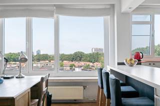 Lichtrijk appartement met terras te koop in Antwerpen

Ben je op zoek naar een energiezuinig appartement te koop in Antwerpen? Deze instapklare woonst op de zevende verdieping werd in 2015 vernieuwd en heeft een bewoonbare oppervlakte van 96 m². Met twee slaapkamers, een gunstig EPC-label B en een uitstekende staat van onderhoud is dit te koop aangeboden appartement in Antwerpen de perfecte plek om jouw nieuwe hoofdstuk te schrijven.

Bij het betreden van het appartement word je verwelkomd in de inkomhal, die toegang geeft tot het gastentoilet. Een dubbele deur met glaspanelen leidt naar de open leefruimte met een houten parketvloer en brede raampartijen die voor een warme sfeer zorgen. De woonkamer en eetkamer lopen vloeiend over in de open keuken, die is uitgerust met een eiland met barfunctie en een kastenwand. Verder bevinden zich in de woonst twee slaapkamers en de badkamer is praktisch ingericht met een ligbad met douchecombinatie en een wastafel.

Aansluitend aan de leefruimte vind je het terras van 3 m² dat zuidoostelijk georiënteerd is. Hier geniet je van een weids en vrij uitzicht over de stad en het omliggende groen.

Enkele jaren geleden werd aan de zuidoostzijde van het appartement, ter hoogte van de slaapkamers, een zonwering geplaatst. Deze zorgt tijdens warme dagen voor extra comfort en helpt de binnentemperatuur aangenaam te houden.

Dankzij het gunstige EPC-label B profiteer je in dit appartement van een uitstekende energiezuinigheid en een lager energieverbruik.

Het appartementsgebouw is voorzien van een lift die je vlot naar de zevende verdieping brengt. Daarnaast kan een privatieve garagebox op het buitenterrein optioneel aangekocht worden twv 35.000€ en is er een gemeenschappelijke, overdekte fietsenstalling aanwezig