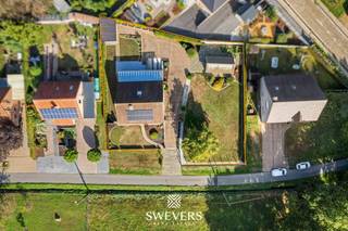 Voor meer info en foto’s, surf naar www.swevers.be – Deze ruime en instapklare bungalow aan de Barenbergseweg 118 in Diest combineert rustig wonen met veel praktische ruimte en extra mogelijkheden. De woning werd gebouwd in 1991, is zeer verzorgd en biedt 253m² bewoonbare oppervlakte op een perceel van 1.442 m² met aanpalende bouwgrond. Op het gelijkvloers vind je een centrale inkomhal met een gastentoilet, een ruime living van 34 m² met salon en eetkamer en een keuken van 15 m². Zowel de leefruimte als de keuken sluiten aan op het terras. Verder zijn er twee slaapkamers van ca. 16 en 15 m² en een badkamer, waardoor grotendeels gelijkvloers wonen perfect mogelijk is. De eerste verdieping omvat een derde slaapkamer van ca. 16 m² en een ruimte van ca. 24 m² die als vierde slaapkamer, bureau of hobbyruimte kan dienen. Twee zolderzones zorgen voor bijkomende bergruimte. Een grote troef is de volledige kelder van 106 m² met berging, wasplaats, provisieruimte en een parkeerkelder van ca. 42 m². De woning beschikt bovendien over zonnepanelen, een thuisbatterij en een goed E-peil. De aanpalende bouwgrond biedt extra mogelijkheden, bijvoorbeeld als ruime tuinzone of, mits de nodige vergunningen, voor een bijkomende woonoplossing. Winkels, scholen en ontspanning liggen op ca. 4 km, het openbaar vervoer op ca. 2,5 km en de snelweg op ca. 7,5 km. Voor meer informatie, bel 011 255 155. Bron bewoonbare oppervlakte: EPC – verslag.