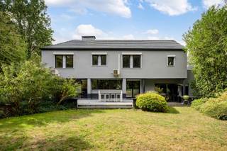 <p><span>Ruime op te frissen woning met 4 slaapkamers, wellness, dubbele garage en tal van mogelijkheden!</span></p><p><span> </span></p><p><span>Deze bijzonder ruime woning combineert een royale bewoonbare oppervlakte met tal van mogelijkheden en een uitstekende bereikbaarheid. De woning is momenteel ingericht als</span></p><p><span>kantoorruimte, maar beschikt over een volwaardige residentiële indeling en kan opnieuw worden ingericht tot een comfortabele gezinswoning.</span></p><p><span> </span></p><p><span>Op het gelijkvloers bevindt zich een ruime inkomhal met gastentoilet. Aan de linkerzijde vinden we een afzonderlijke bureauruimte, ideaal als thuiskantoor of praktijkruimte.</span></p><p><span>De royale leefruimte biedt plaats aan zowel een ruime eetplaats als een aparte, gezellige zithoek met gashaard alsook een TV-ruimte.</span></p><p><span>Grote raampartijen zorgen voor veel natuurlijk licht en zijn op het gelijkvloers voorzien van zonneluifels. De woning is hoofdzakelijk afgewerkt met tegelvloeren en beschikt over in de vloer geïntegreerde convectoren.</span></p><p><span>De zeer ruime keuken biedt veel werk- en bergruimte en geeft via de achterdeur rechtstreeks toegang tot het terras en de tuin. Aansluitend bevinden zich nog een praktische berging en bijkeuken.</span></p><p><span>Een absolute troef is de grote polyvalente ruimte, momenteel ingericht met een bar. Onder de huidige vloer bevindt zich het oorspronkelijke binnenzwembad. De vloerconstructie kan opnieuw worden verwijderd, waardoor het zwembad opnieuw in gebruik kan worden genomen en hier een prachtige ontspanningsruimte kan worden gecreëerd. Aansluitend bevindt zich een aparte wellnessruimte met stoomcabine en sanitair.</span></p><p><span> </span></p><p><span>Op de verdieping bevinden zich vier volwaardige slaapkamers. De master bedroom beschikt over ingebouwde kasten. Eén van de slaapkamers heeft een eigen douchekamer. Daarnaast is er een ruime badkamer met ligbad, douche, lavabo en toilet. Ook de verdieping is hoofdzakelijk voorzien van tegelvloeren.</span></p><p><span> </span></p><p><span>Ook aan praktische ruimte is er geen gebrek. De woning beschikt over een zeer ruime, volledig betegelde kelder en een dubbele inpandige garage, rechtstreeks bereikbaar via de oprit.</span></p><p><span> </span></p><p><span>Voor extra comfort is zowel op het gelijkvloers als op de verdieping airconditioning aanwezig. Daarnaast beschikt de woning over een alarmsysteem, een gashaard en werd de verwarmingsinstallatie ongeveer vier jaar geleden vernieuwd.</span></p><p><span>Ook energetisch is er een belangrijke troef: de woning heeft een EPC-score van C, waardoor er geen renovatieverplichting van toepassing is.</span></p><p><span> </span></p><p><span>Buiten valt meteen de uitzonderlijk ruime parking aan de voorzijde op, met plaats voor meerdere wagens. Achteraan geniet u van een mooi terras en een ruime, groene tuin. De achterliggende groene omgeving zorgt bovendien voor een aangenaam en open karakter.</span></p><p><span> </span></p><p><span>De woning kan op bepaalde punten naar eigen smaak worden opgefrist, maar biedt dankzij haar uitzonderlijke ruimtes, vier slaapkamers, binnenzwembad en wellnessmogelijkheden, dubbele garage en ruime buitenomgeving bijzonder veel potentieel. Ook voor wie wonen en werken wil combineren, biedt dit pand interessante mogelijkheden.</span></p><p><span> </span></p><p><span>Troeven:</span></p><p><span> - EPC-score C geen renovatieverplichting</span></p><p><span> - 4 slaapkamers</span></p><p><span> - Zeer ruime leefruimtes</span></p><p><span> - Grote keuken met aansluitende berging en bijkeuken</span></p><p><span> - Binnenzwembad aanwezig onder de huidige vloer</span></p><p><span> - Wellnessruimte met stoomcabine</span></p><p><span> - Airconditioning op gelijkvloers en verdieping</span></p><p><span>- Gashaard</span></p><p><span> - Vloerconvectoren</span></p><p><span>- Verwarmingsinstallatie ca. 4 jaar geleden vernieuwd</span></p><p><span>- Grote, volledig betegelde kelder</span></p><p><span> - Dubbele inpandige garage</span></p><p><span>- Uitzonderlijk ruime parking vooraan</span></p><p><span> - Mooi terras en groene tuin</span></p><p><span>- Achterliggende groene omgeving</span></p><p><span>- Alarmsysteem</span></p><p><span> - Interessant voor combinatie wonen en werken</span></p><p><span> - Goede bereikbaarheid</span></p>