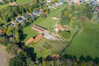 Verscholen in het groen, midden in het centrum van Oud-Turnhout, ligt een domein waar rust, privacy en ruimte samenkomen. Een dubbele toegangspoort en een prachtig aangelegde oprit vormen de entree tot dit karaktervolle landhuis. Hier geniet je van een landelijk woongevoel op circa 3 hectare, met het gemak van winkels en dagelijkse voorzieningen vlakbij. Een bijzondere combinatie die de ligging nog een extra meerwaarde geeft.

Het gelijkvloers biedt royale leefruimtes met een living, gezellige zithoek en keuken, waar het aangenaam thuiskomen en ontvangen is. Een afzonderlijk bureau vormt een rustige werkplek. De veranda aan de voorzijde en het mooie overdekte terras met buitenkeuken aan de achterzijde verbinden het wonen met het buitenleven: van ontspannen genieten van het groen tot uitgebreid tafelen met familie en vrienden. Een ruime berging, wasplaats en wijnkelder vervolledigen het comfort.
Ook de mastersuite met dressing, badkamer en aparte ingang bevindt zich op het gelijkvloers. 

Op de verdieping bevinden zich vier zeer royale slaapkamers, een ruime berging en een inpandig gedeelte ingericht als appartement, met eigen leefruimte, keuken en badkamer. Ideaal voor gezinsleden die graag een eigen plek binnen de woning hebben. De woning beschikt over een grote bergzolder, bereikbaar via vlisotrap.

Buiten ontvouwt zich een uitgestrekt groen domein met vijver, terrassen en zwembad. Van een rustige ochtend aan het water tot een lange zomeravond met vrienden: hier krijgt het buitenleven alle ruimte, in de privacy van de eigen tuin.

Het voormalige fabriekje, de loodsen en het koetshuis geven het eigendom een karakter dat verder reikt dan de hoofdwoning. Het fabriekje draagt de geschiedenis van de plek met zich mee. Samen met de loodsen biedt het een aanzienlijk geheel aan extra binnenruimte. De ruime boogloods versterkt die bijzondere troef.

Het charmante koetshuis voegt een persoonlijk afwerkingsproject toe aan het geheel. Binnen is reeds een indeling aangebracht met het oog op verdere afwerking als woning. 

Bijzonderheden:

Zeer rustige centrumligging met volop privacy.

Dubbele toegangspoort en prachtig aangelegde oprit.

Riant grondstuk van 28.022 m² met vijver.

Mastersuite, vier royale slaapkamers en extra inpandige leefruimte.

Voormalig fabriekje, loodsen en koetshuis.

EPC A: 50 kWh/m² per jaar.

Warmtepompen, 42 zonnepanelen en thuisbatterij van 10 kWh.

Conforme elektriciteit.