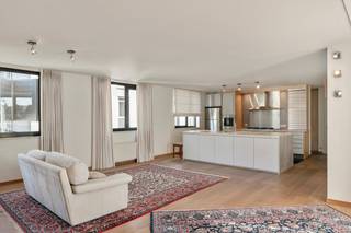 Op de vierde verdieping van een zeer goed onderhouden gebouw bevindt zich dit lichtrijke en instapklare appartement van ca. 125 m², gelegen in de Molenstraat. Dankzij de uitzonderlijk brede gevel geniet het appartement van veel natuurlijke lichtinval en een aangenaam ruimtegevoel.<br /><br />Bij het betreden van het appartement komt u in de inkomhal met apart gastentoilet. Van hieruit bereikt u de ruime leefruimte met open keuken. De grote raampartijen zorgen voor een open en luchtig gevoel en geven rechtstreeks toegang tot het eerste zuidgerichte terras met uitzicht op de binnentuin.<br /><br />De open keuken werd vernieuwd en is praktisch ingericht, met aansluitend een berging met aansluiting voor wasmachine en droogkast.<br /><br />Via de nachthal bereikt u de twee volwaardige slaapkamers. De hoofdslaapkamer geeft uit op een tweede, eveneens zuidgericht terras. De badkamer is uitgerust met een ligbad, douche en dubbele lavabo.<br /><br />Het appartement werd zeer goed onderhouden en is afgewerkt met parketvloeren en ingemaakte kasten. Dankzij de recente vernieuwingen aan het gebouw, waaronder de lift (2025), zijn er geen grote kosten te verwachten.<br /><br />Met zijn lichtinval, twee terrassen en kwalitatieve afwerking is dit een ideale keuze voor comfortabel en zorgeloos wonen.<br /><br />Bijzonderheden<br />EPC B<br />Asbestveilig attest<br />Vernieuwde lift (2025)<br />Garagebox optioneel (€45.000)<br />AK: ca. €175/maand