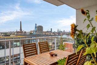 Op de zesde verdieping van De Faar, in de duurzame wijk De Nieuwe Dokken, bevindt zich dit luxueuze appartement met drie slaapkamers, twee badkamers en een prachtig uitzicht.<br /><br />De royale leefruimte omvat een ruime open keuken met plaats voor een volwaardige eetkamer en een aansluitende, gezellige televisiehoek. Van hieruit bereikt u het terras, met zijdelings uitzicht op het water en de drie torens van Gent: een bijzonder mooi stedelijk panorama.<br /><br />Het appartement beschikt over drie slaapkamers. De eerste badkamer is uitgerust met een ligbad en toilet; de tweede met een ruime inloopdouche. Daarnaast is er een afzonderlijk gastentoilet en een praktische, ruime berging. <br /><br />De Faar ligt aan het Handelsdok, tussen water en groen en op wandelafstand van de historische binnenstad. Via de Batavia- en Matadibrug bereikt u vlot het centrum. Ook station Gent-Dampoort en de Gentse ring zijn gemakkelijk bereikbaar.<br /><br />Een ondergrondse parkeerplaats kan worden bijgekocht voor € 30.000. Een extra ondergrondse berging is verkrijgbaar voor € 7.500, fietsenstalling is inbegrepen in de prijs.<br /><br />Een uitzonderlijk appartement voor wie ruimte, comfort, duurzaamheid en een uniek uitzicht wil combineren op een van de aantrekkelijkste woonlocaties van Gent.
