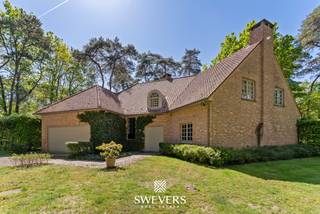 Voor meer info en foto’s, surf naar www.swevers.be – Deze tijdloze villa is gelegen op een unieke locatie omgeven door groen in exclusief woonparkgebied in Viversel. De woning straalt klasse uit en biedt tegelijk een warme, uitnodigende sfeer. Met een bewoonbare oppervlakte van 275 m² op een zuidgericht perceel van 28a69 geniet u hier van een comfortabele woonomgeving omringd door groen. De woning verwelkomt u in een statige inkomhal met elegante trap. Via dubbele glazen deuren bereikt u de ruime en lichtrijke leefruimte van 65 m², met zicht op het terras en omliggend groen. De vernieuwde keuken van 30 m² is volledig uitgerust en praktisch ingericht, met naastgelegen berging/wasplaats en dubbele inpandige garage. Op het gelijkvloers vindt u ook een bureauruimte, ideaal voor thuiswerk. Op de verdieping zijn er vier slaapkamers van 17 m² tot 24 m². De masterbedroom beschikt over een aansluitende dressing en badkamer met bad en douche, die reeds werd gerenoveerd. Twee ruime slaapkamers grenzen aan elkaar en delen een douchekamer. De 4e slaapkamer doet in dit geval dienst als hobbykamer. De tuin rondom de woning zorgt voor een sterke connectie tussen binnen en buiten en biedt alle privacy om van het buitenleven te genieten. De ligging is vlot bereikbaar, op 2 km van de snelweg, met openbaar vervoer op 400 meter en ontspanning, restaurants en sportfaciliteiten op 1 km. Voor meer informatie, bel 011 255 155. Bron bewoonbare oppervlakte: EPC – verslag.