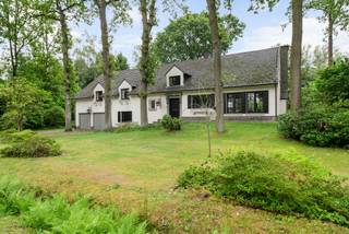 Cachée dans un environnement calme et résidentiel, cette villa de caractère à plusieurs niveaux se trouve sur un magnifique terrain. La maison combine une ambiance chaleureuse et authentique avec des volumes de vie étonnamment spacieux et une disposition ludique et réfléchie.<br /><br />Disposition<br />Par le hall d'entrée élégant avec sol en pierre naturelle, nous atteignons le cœur de la maison.<br /><br />Un demi-niveau plus bas, dans l'aile gauche, se trouve un grand espace bureau ou une chambre supplémentaire, complété par une buanderie pratique et un garage double intégré.<br /><br />Dans l'aile droite, un demi-niveau plus bas, nous trouvons un sous-sol particulièrement spacieux avec des caves de rangement ou une cave à vin et une salle technique.<br /><br />De retour au niveau du hall d'entrée, nous trouvons les espaces de vie. La cuisine entièrement équipée dispose de beaucoup d'espace de travail et de rangement et bénéficie d'une belle vue sur le jardin. Ensuite, la salle à manger spacieuse qui se fond parfaitement dans le salon confortable. Des poutres en bois authentiques, une imposante cheminée et de grandes baies vitrées créent une atmosphère chaleureuse et intemporelle et un magnifique contact avec la verdure environnante.<br /><br />La pièce de vie agréable forme un espace de vie supplémentaire où vous pourrez profiter du jardin toute l'année et donne un accès direct à la terrasse.<br /><br />Un demi-niveau plus haut se trouve l'aile de nuit. Le spacieux palier avec placards intégrés donne accès à trois chambres à coucher complètes et deux salles de bains. La chambre principale dispose d'un mur entier de placards intégrés et bénéficie d'une vue magnifique sur le jardin depuis la large terrasse.<br /><br />Par l'escalier central dans le hall d'entrée, nous atteignons l'étage supérieur. Ici se trouve un espace polyvalent particulièrement spacieux avec un volume impressionnant et de nombreuses possibilités. Cet étage peut être aménagé parfaitement en chambres supplémentaires, une suite parentale généreuse avec dressing et salle de bains, un espace de loisirs, une salle de sport ou un bureau à domicile.<br /><br />Au-dessus de l'aile de nuit se trouve un grenier pratique.<br /><br />Espace extérieur:<br />La maison est située sur un magnifique terrain mature entièrement entouré de verdure et offrant une intimité optimale. La grande terrasse est directement accessible depuis les espaces de vie.<br /><br />La cheminée extérieure en briques authentiques apporte une ambiance supplémentaire.<br /><br />Caractéristiques:<br />- Emplacement résidentiel calme<br />- Architecture à plusieurs niveaux de caractère<br />- 4 chambres et 2 salles de bains<br />- Grand étage supérieur polyvalent avec possibilités d'extension