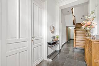 In het historische centrum van Ieper bevindt zich dit uitzonderlijk stijlvolle herenhuis waar authentieke charme en hedendaags wooncomfort naadloos samenvloeien. Deze instapklare woning werd luxueus afgewerkt met duurzame en kwalitatieve materialen en biedt een zee aan ruimte, een inpandige garage, een volledig ommuurde zonnige tuin én tal van mogelijkheden. De huidige eigenaars baten bovendien twee slaapkamers succesvol uit als B&B, waardoor deze eigendom zich eveneens uitstekend leent voor een combinatie van wonen en ondernemen.<br /><br />Via de royale inkomhal met prachtige authentieke trappenhal, vestiaire en gastentoilet wordt u meteen ondergedompeld in de unieke sfeer van deze woning. Achter de authentieke dubbele deur bevindt zich een stijlvolle voorplaats, momenteel ingericht als ontbijtruimte voor de B&B-gasten. Dankzij de karaktervolle vierdelige deur kan deze ruimte volledig afgesloten of net open betrokken worden bij de luxueuze leefkeuken.<br /><br />De volledig ingerichte open keuken vormt het kloppend hart van de woning en is uitgerust met alle comfort: een inductiekookplaat, dampkap, twee ingebouwde koelkasten, vaatwasser, oven, stoomoven, microgolfoven en koffiemachine. Aansluitend bevindt zich de uitzonderlijk lichtrijke leefruimte met een ruime eetplaats en een gezellige zithoek waar de sfeervolle gashaard voor extra warmte en gezelligheid zorgt.<br /><br />Verder beschikt het gelijkvloers over een praktische wasplaats met maatkasten, voorzien van aansluitingen voor wasmachine en droogkast en een lavabo. Via de ruime berging bereikt u de inpandige garage met sectionale poort en laadpaal.<br /><br />Op de eerste verdieping bevindt zich de prachtige master suite met een stijlvolle dressing voorzien van heel wat maatkasten en een ruime slaapkamer die discreet kan worden afgesloten met verborgen schuifdeuren. De luxueuze badkamer is uitgerust met een vrijstaand ligbad, een ruime inloopdouche en een dubbel lavabomeubel.<br /><br />Daarnaast bevinden zich op deze verdieping nog twee bijzonder ruime slaapkamers, elk voorzien van een eigen en-suite badkamer met douche, toilet en dubbel lavabomeubel. Deze kamers worden momenteel succesvol uitgebaat als B&B. Verder is er nog een technische ruimte die tevens perfect dienst kan doen als bureau. Via een tweede trap is er bovendien een rechtstreekse verbinding met de berging op het gelijkvloers.<br /><br />De tweede verdieping telt nog drie volwaardige slaapkamers, waarvan één beschikt over een ruime mezzanine. Op deze verdieping bevindt zich eveneens een apart toilet.<br /><br />Ook de kelderverdieping biedt heel wat extra bergruimte en bestaat uit drie afzonderlijke ruimtes, waarvan één ingericht is als wijnkelder.<br /><br />Buiten geniet u in alle privacy van de volledig ommuurde, zonnige stadstuin met twee gezellige terrassen, sfeervolle geïntegreerde buitenverlichting en een praktische tuinberging.<br /><br />Extra troeven<br />Instapklaar en luxueus afgewerkt<br />Authentieke elementen zoals de prachtige trappenhal, hoge plafonds en karaktervolle gevel<br />Zes volwaardige slaapkamers<br />Mogelijkheid tot B&B of kangoeroewonen<br />Inpandige garage met sectionale poort en laadpaal<br />29 zonnepanelen (5.510 Wp)<br />Regenwatervoorziening<br />Maatwerk met talrijke ingebouwde kasten<br />Inbouwverlichting<br />Gordijnen op maat<br />Droge kelder met authentieke wijnkelder<br />Volledig ommuurde zonnige stadstuin met twee terrassen<br /><br />Bent u op zoek naar een exclusieve herenwoning waar authenticiteit, ruimte, luxe en veelzijdigheid samenkomen op een toplocatie in het centrum van Ieper? Dan is deze unieke eigendom zonder twijfel een bezoek waard.
