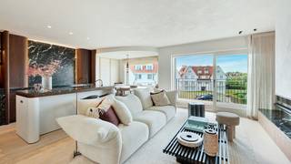Op een uitzonderlijke en zonovergoten ligging, pal aan de Wandeldijk en het Zwin, bevindt zich dit hoogstaand afgewerkte appartement dat uitblinkt in stijl, comfort en uitzicht.<br /><br />Bij het betreden van het appartement wordt u verwelkomd in een ruime inkomhal met vestiaire en gastentoilet. De indrukwekkend brede leefruimte is voorzien van een elegant salon met gashaard en opent naadloos naar het perfect georiënteerde zonneterras.<br /><br />De leefkeuken, uitgerust met Miele-toestellen, met afwerking in marmer straalt tijdloze klasse en verfijning uit. Aansluitend een gezellige eethoek.<br /><br />De master bedroom beschikt over een luxueuze en suite douchekamer. Ook de tweede en derde slaapkamer genieten elk van een eigen douchekamer, allen met zeezicht.<br /><br />Extra comfort: Privatieve kelderberging, fietsenberging en conciërgedienst<br /><br />Mogelijkheid tot aankoop van een privatieve parkeerplaats.