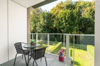 Op een bijzonder mooie en historische locatie in Gent bevindt zich deze recente assistentiewoning met twee slaapkamers, gelegen op de site Abraham Voortman. Een unieke omgeving waar rust en groen hand in hand gaan met de nabijheid van het stadscentrum.<br /><br />De assistentiewoning beschikt over een aangename en lichtrijke leefruimte met open keuken. Vanuit de leefruimte heeft u een prachtig zicht over het Vogelenzangpark en toegang tot het aansluitende, zuidwestgerichte terras. Een heerlijke plek om te genieten van de namiddag- en avondzon, met het groen als bijzonder decor.<br /><br />De open keuken is ingericht met oog voor comfort en beschikt onder meer over een in hoogte verstelbaar keukenblad. Verder omvat de woning twee volwaardige slaapkamers, een praktische berging en een comfortabele badkamer die zowel vanuit de slaapkamer als vanuit de nachthal toegankelijk is. Er is een privatieve kelderberging en een gemeenschappelijke fietsenberging.<br /><br />Als bewoner geniet u hier van de vrijheid en privacy van een eigen appartement, met tegelijk de geruststelling van een professionele woonomgeving. Een woonassistent staat ter beschikking en via het noodoproepsysteem is er 24/7 permanentie. Wie dat wenst, kan bovendien gebruikmaken van bijkomende diensten en zorgondersteuning.<br /><br />Ook de aanwezigheid van (zorg)Hotel Den Briel op de site vormt een mooie meerwaarde. Bewoners kunnen er onder meer terecht in het restaurant, dat beschikt over een aangenaam terras met rechtstreekse toegang tot het Vogelenzangpark, en genieten van diverse andere faciliteiten.<br /><br />De ligging is bijzonder: u woont hier in alle rust op een historische site, met een prachtig groen uitzicht, terwijl het centrum van Gent, winkels, horeca, het ziekenhuis (AZ Sint-Lucas) en openbaar vervoer zich op korte afstand bevinden.<br /><br />Een recente en comfortabele assistentiewoning (oppervlakte 113,18m² incl. terras en kelderberging) op een uitzonderlijke locatie, met het park als dagelijks decor en de stad binnen handbereik.