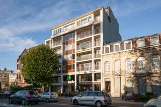 <p>Aan de Mechelsesteenweg 7 in Mortsel ligt dit uitzonderlijk ruime appartement op de eerste verdieping van residentie Ter Linde. Het gebouw dateert van 1976, is goed onderhouden en ligt midden in het commerciële centrum van Mortsel. Met een bruikbare oppervlakte van 175 m², vier slaapkamers en twee terrassen krijg je hier veel ruimte voor je budget.</p>
<p>Het appartement is wel aan een grondige renovatie toe. De afwerking is gedateerd: keuken, badkamer, vloeren en muren vragen allemaal een vernieuwing. Wie die stap zet, kan de ruimte volledig naar eigen smaak indelen en afwerken.</p>
<p>De buurt</p>
<p>Je woont hier in het hart van Mortsel. Winkels, horeca, scholen en het openbaar vervoer liggen in de nabijheid, en de grote verbindingswegen zijn vlot bereikbaar.</p>
<p>Indeling</p>
<p>Vanuit de inkomhal kom je in de leefruimte van circa 80 m². Ze heeft een visgraatparket, sierlijsten aan het plafond en vloerconvectoren langs de ramen. Grote raampartijen langs twee zijden en brede schuiframen naar het voorterras zorgen voor veel daglicht. De ruimte is zo groot dat er zelfs nog een vijfde slaapkamer bij kan.</p>
<p>De open keuken sluit aan op de leefruimte via een bar en heeft een tegelvloer. Ook vanuit de keuken stap je rechtstreeks het terras op.</p>
<p>In het nachtgedeelte liggen vier slaapkamers van 7,5, 9,5, 11 en 13,5 m². De grootste slaapkamer heeft een wand met ingebouwde kasten en een deur naar het achterterras.</p>
<p>De ruime badkamer is voorzien van een ligbad, een aparte douche, twee lavabo's en een toilet. Daarnaast is er een berging met lavabo en een tweede toilet, handig als wasplaats.</p>
<p>Buiten</p>
<p>Het appartement heeft twee terrassen. Het voorterras, bereikbaar vanuit de leefruimte en de keuken, kijkt uit over de groene middenberm en de bomen van de Mechelsesteenweg. Het achterterras ligt aan de rustige achterkant van het gebouw en kijkt uit op hoge bomen en groen.</p>
<p>Technisch</p>
<p>Het appartement heeft aluminium schrijnwerk met deels dubbele en deels enkele beglazing. De verwarming gebeurt via een collectieve centrale verwarming op gas. Ondanks de nodige renovatie haalt het appartement al een EPC-label B. De elektrische installatie is niet conform en moet bij de renovatie vernieuwd worden.</p>
<p>Gebouw en kosten</p>
<p>De lift werd reeds vernieuwd en het dak van het gebouw is geïsoleerd volgens de huidige normen. De vaste kosten bedragen ongeveer € 375 per maand. Daarin zitten de provisie voor verwarming en water, de syndicus, de verzekering van het gebouw, het onderhoud en de verlichting van de gemeenschappelijke delen, het onderhoud van de lift en het reservefonds.</p>
<p>Troeven: 175 m² bruikbare oppervlakte, leefruimte van 80 m², 4 slaapkamers met optie op een vijfde, terras aan voor- en achterzijde, vernieuwde lift, geïsoleerd dak, EPC-label B, centrale ligging in Mortsel.</p>
<p>EPC: 135 kWh/m².jaar, Asbestattest: asbestveilig Elektrische installatie: niet conform Overstromingsgevoeligheid: P-score klasse B, G-score klasse A Stedenbouwkundige info: [vergunningstoestand, bestemming, dagvaarding, voorkooprecht, verkavelingsvergunning]</p>
<p>Interesse? Contacteer ons voor een bezoek</p>