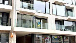 Dit nieuwbouwappartement op de eerste verdieping verrast door zijn royale ruimtes en hoogwaardige afwerking.<br /><br />Bij het binnenkomen wordt u verwelkomd in een bijzonder ruime inkomhal, voorzien van een praktische maatwerkkast met geïntegreerde zitbank.<br /><br />De lichtrijke leefruimte met stijlvolle parketvloer geniet dankzij de volledige raamwand van een aangename lichtinval en sluit naadloos aan op de open volledig uitgeruste keuken met gezellige ontbijtbar.<br />Aansluitend bevindt zich een ruime berging met aansluiting voor wasmachine en een handig werkblad.<br /><br />Verder beschikt het appartement over twee volwaardige slaapkamers, een moderne badkamer met inloopdouche en een afzonderlijk toilet.<br /><br />Buiten geniet u zowel van een terras aan de achterzijde als van een ruim balkon aan de voorzijde.<br /><br />Een absolute meerwaarde is de inbegrepen ruime garagebox.<br /><br />Het appartement beschikt over vloerverwarming en daarnaast zijn er privatieve zonnepanelen aanwezig wat bijdraagt aan een lagere energiefactuur.<br /><br />Het appartement werd bovendien volledig nieuw geschilderd en is zeer binnenkort beschikbaar.<br /><br />Huurprijs te vermeerderen met 50 EUR gemeenschappelijke kosten per maand.<br /><br />EPB nieuwbouw i.a. <br /><br /><u><strong>Bezoeken?</strong></u><br />U kunt dit eenvoudig zelf inplannen via de afsprakenlink op onze website voor het bezoekmoment van <u>donderdag 9 juli</u>.
