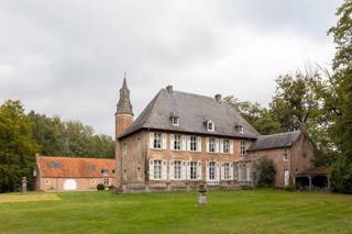 <p><span><span>Kasteelhoeve op uniek perceel in Tielen</span></span></p><p><span><span>In het groene landschap van de Kempen, vlak bij het recreatiedomein van De Hoge Rielen, bevindt zich het historische domein Tielenhof. Dit omgrachte kasteelgoed, waarvan de oorsprong teruggaat tot de 14de eeuw, ligt in het charmante dorp Tielen. Ondanks de rustige en landelijke setting geniet het domein van een vlotte bereikbaarheid: het treinstation van Tielen ligt op slechts enkele minuten wandelen, op ongeveer 800 meter afstand.</span></span></p><p><span><span>De geschiedenis van Tielenhof gaat eeuwen terug. Vermoedelijk liet Hendrik van Duffel rond 1350 op deze plek een kasteel optrekken dat lange tijd dienstdeed als residentie van de heren van Tielen. Doorheen de eeuwen wisselde het domein meermaals van eigenaar via huwelijken en erfenissen binnen verschillende adellijke families. Pas in 1958 werd het voor het eerst verkocht buiten deze kringen. Het kasteel kende meerdere verbouwingen: een ingrijpende aanpassing in 1830 transformeerde het tot een zomerresidentie, waarbij een deel van het oorspronkelijke middeleeuwse karakter verdween. Tijdens een restauratiecampagne in de jaren 1970 werden opnieuw historische elementen uit de 16de en 17de eeuw in ere hersteld, waaronder kruiskozijnen en de kenmerkende traptoren.</span></span></p><p><span><span>Vandaag vormt Tielenhof een karaktervol L-vormig geheel, opgebouwd in traditionele baksteen en zandsteen. De hoofdvleugel telt twee bouwlagen en wordt afgedekt met een steil schilddak. Het geheel wordt aangevuld met verschillende bijgebouwen, waaronder een barok koetshuis uit 1686 en een poortgebouw met houten ophaalbrug. De toegang tot het domein verloopt via de indrukwekkende Kasteeldreef: een circa 230 meter lange, gekasseide beukendreef die leidt naar het omgrachte terrein van ongeveer 1,7 hectare. Kastelen van dit type zijn uitzonderlijk in de Kempense regio en maken van Tielenhof een bijzonder stukje erfgoed.</span></span></p><p><span><span>De ligging midden in een natuurgebied maakt het domein uniek, maar vraagt tegelijk om een doordachte invulling. De bestemming blijft hoofdzakelijk residentieel, al zijn er diverse interessante mogelijkheden denkbaar: bijvoorbeeld een woonproject met mantelzorg of kangoeroewonen, het combineren van wonen met een kleinschalige horecazaak zoals een bistro of restaurant, of een cohousingconcept waarbij het karakter van één huishouden behouden blijft. Voor wie op zoek is naar een uitzonderlijke woonplek met geschiedenis, natuur en potentieel, biedt Tielenhof een zeldzame kans.</span></span></p><p> </p><p><span><span>Interesse? Bel ons nu voor het inplannen van een afspraak op 0489/89.49.74.</span></span></p>