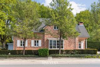 Voor meer info en foto’s, surf naar www.swevers.be – Deze open bebouwing op Laan op Heusden 47 in Koersel werd gebouwd in 2006 en biedt met een bewoonbare oppervlakte van 256 m² heel wat ruimte en mogelijkheden. De woning is op te frissen, maar beschikt over een doordachte indeling en een sterke basis om er een eigentijdse en warme thuis van te maken. Op het gelijkvloers kom je binnen via de inkomhal met gastentoilet. Centraal ligt de eetkamer, met aansluitend een aparte living van 18,90 m² met houthaard. De ruime keuken van 28,30 m² biedt plaats voor een eethoek, is uitgerust met een gashaard en geeft rechtstreeks uit op terras en tuin. Verder zijn er een wasplaats, een slaapkamer van ca. 15 m², een dressing, een badkamer met ligbad en dubbele lavabo en een aparte tuinkamer van 14,50 m² met gashaard. Op de verdieping zijn er nog 2 ruime slaapkamers van ca. 20,43 m² en 22,19 m², een tweede badkamer en een mooie vide met ingerichte bibliotheek. Extra bergruimte is er via inbouwkasten en de zolder. Het perceel heeft een oppervlakte van 2876 m², waarvan de bouwgrond bestaat uit 7a55ca. Buiten geniet je van een private noordoostgerichte tuin met bekabeling voor tuinverlichting. Bijkomende troeven zijn de regenwaterput van 5.000 liter, voorbereiding voor luidsprekers en een recent onderhouden ketel. Rustig gelegen, met scholen, winkels, openbaar vervoer en ontspanning in de nabije omgeving en een vlotte verbinding naar de snelweg. Voor meer informatie, bel 011 255 155. Bron bewoonbare oppervlakte: EPC – verslag.