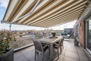 [[ DIT PAND NEEMT DEEL AAN DE ERA OPEN HUIZEN DAG OP 13/6 VAN 9:30 TOT 10:30 ]]
<p>Ben je opzoek naar een rustig gelegen dakappartement dat tot in de puntjes onderhouden werd? Lees hier dan zeker even verder!</p>

<p>Dit prachtige appartement is klaar om meteen van te genieten en bevindt zich in een verzorgd gebouw. Met twee indrukwekkende dakterrassen van elk 70m² biedt dit appartement volop ruimte om buiten te leven en te ontspannen. Dit zijn slecht enkele troeven van deze woning!</p>

<p>Indeling:</p>

<p>Bij binnenkomst word je verwelkomd in de inkomhal (12m²), die toegang geeft tot de zonovergoten woonkamer met een moderne open keuken (54m²). De keuken is voorzien van alle nodige toestellen om je heerlijke maaltijden voor te bereiden. Vanuit de woonkamer stap je direct op de twee unieke terrassen, elk aan een zijde van het appartement. Zo geniet je de hele dag van de zon en kan je in alle rust ontspannen. Verder beschikt het appartement over drie comfortabele slaapkamers (7-8-16m²), een ruime badkamer (12m²), een aparte wasplaats en een gastentoilet. Alles is tot in de puntjes afgewerkt en voorzien van alle comfort. Geniet van de rust, de zon en het uitzicht, terwijl je toch alle voorzieningen binnen handbereik hebt. Dit is een zeldzame kans voor wie houdt van modern wonen in een groene en serene omgeving. Bij het appartement hoort een kelderberging en dient de autostaanplaats bij aangekocht te worden voor €25.000.</p>

<p>Zou deze woning wel eens jouw nieuwe thuis kunnen worden? Laat ons dan snel iets weten en plan een bezoek in!</p>