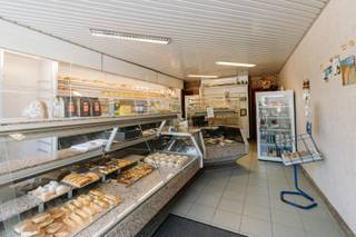 <p>In het hart van Rumst, op een opvallende en vlot bereikbare locatie onder de kerktoren, biedt zich een unieke kans aan: de <strong>overname van een gevestigde bakkerij mét het bijhorende eigendom</strong>. Deze authentieke handelszaak geniet al jaren een sterke lokale verankering en combineert een instapklare professionele activiteit met comfortabel wonen op dezelfde locatie.</p><p><br /></p><p>Je komt binnen in de winkelruimte, die vandaag praktisch is ingericht maar tegelijk makkelijk aangepast kan worden aan eigen wensen. De typische geur van vers gebakken brood maakt meteen duidelijk dat dit een plek is met geschiedenis en ambacht. Achteraan ligt de bakkerij zelf, uitgerust met kwalitatieve ovens, kneedmachines en rijskasten — alles wat nodig is om meteen aan de slag te gaan.</p><p>Achter het gebouw is er nog een garage en een aangenaam tuintje, handig voor leveringen of gewoon als rustige buitenruimte. Met de Nete als achterbuur kom je hier bovendien helemaal tot rust.</p><p>Boven de zaak bevindt zich een duplex appartement dat mee is met zijn tijd, met onder andere drie slaapkamers en het comfort dat je vandaag verwacht.</p><p>Een mooie opportuniteit voor wie droomt van een eigen zaak met karakter, of voor een bestaande bakker die zich verder lokaal wil verankeren op een sterke locatie.</p><p><br /></p><p><strong>Troeven: </strong>Centrale ligging – Instapklare bakkerij – Wonen en werken te combineren – Authentiek karakter – Rustige achterzijde</p>
