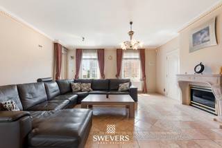 Voor meer info en foto’s, surf naar www.swevers.be – In de Groenstraat 42A in Glabbeek wacht deze uitstekend onderhouden villa uit 2003 op een nieuw gezin. Met een bewoonbare oppervlakte van 303 m² en een perceel van 22a 96ca biedt deze woning een zee aan ruimte en comfort. Doorheen de jaren werden diverse verbeteringen uitgevoerd, waaronder airconditioning, maatwerkkasten en een frisse schilderbeurt. De lichtrijke woonkamer van bijna 50 m² sluit aan op een gezellige veranda, terwijl de ruime keuken met kookeiland en praktische bijkeuken ideaal is voor het gezinsleven. Op het gelijkvloers bevinden zich verder een badkamer, bureau, gastentoilet, berging en een inpandige garage voor 2 à 3 wagens. De eerste verdieping telt drie ruime slaapkamers, een badkamer en twee dressings. De volledig afgewerkte zolder is ingericht als twee extra slaapkamers, waardoor de woning in totaal over vijf slaapkamers beschikt, maar kan ook perfect dienen als hobbyruimte of bureau. De volledige onderkeldering van 97 m² biedt tal van mogelijkheden voor opslag, werkplaats of hobbyruimte. Buiten geniet u van een verzorgde tuin met terrassen, petanquebaan en ruime grasvelden. Extra comfort wordt verzekerd door airconditioning, een alarmsysteem, elektrische garagepoorten en elektrische rolluiken. De rustige ligging combineert een vlotte bereikbaarheid met winkels, scholen, openbaar vervoer en de E40 en E314 in de nabije omgeving. Een instapklare en bijzonder complete villa waar ruimte, comfort en functionaliteit perfect samenkomen. Voor meer informatie, bel 011 255 155. Bron bewoonbare oppervlakte: EPC – verslag.
