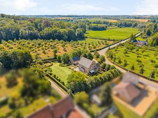 Cette villa pleine de caractère et intemporelle, située sur un terrain exceptionnel de 38a 64ca, bénéficie d'un emplacement unique dans la vallée verdoyante de la Mombeek et de la Fonteinbeek, à proximité du château historique de Kolmont.<br />Avec une superficie habitable de 367 m² (selon le PEB) et une finition de haute qualité, cette propriété offre un jeu harmonieux d'espace, de confort et d'intimité.<br />La maison dispose d'un hall d'entrée imposant avec un escalier, un bureau séparé, un salon lumineux, une cuisine entièrement équipée avec coin petit-déjeuner, une buanderie pratique, 3 chambres et 2 salles de bains. De plus, la villa est entièrement sous-sol et dispose d'un grenier isolé.<br />Le bâtiment annexe multifonctionnel comprend un studio aménagé et 3 garages intégrés. Le domaine entièrement clôturé est fermé par deux portails d'accès automatiques.<br /><br />Rez-de-chaussée:<br /><br />Hall d'entrée élégant avec sol en pierre naturelle et toilettes japonaises séparées. Le salon spacieux avec parquet en chêne massif et une cheminée chaleureuse comprend un coin salon confortable et une salle à manger attenante. Le bureau séparé peut être fermé par des portes de château authentiques recyclées. La cuisine récente entièrement équipée avec coin petit-déjeuner offre un accès direct à la terrasse et au jardin par des portes doubles. À côté se trouve une buanderie pratique avec entrée latérale, équipée d'armoires sur mesure, d'un évier et de connexions pour le lave-linge et le sèche-linge.<br /><br />Étage:<br /><br />Par l'escalier en bois élégant, vous atteignez le palier, fini avec du parquet. Ici se trouve la suite parentale généreuse avec un dressing magnifiquement fini, qui peut également être transformé en une chambre supplémentaire. La salle de bains attenante est équipée d'une baignoire, d'une douche à l'italienne et d'un lavabo double. Un espace de rangement intégré a été discrètement dissimulé derrière des armoires sur mesure.<br /><br />De plus, cet étage compte deux chambres spacieuses, toutes deux équipées de mobilier sur mesure et d'un lavabo privé. Un espace bien-être partagé avec douche solaire est accessible depuis les deux chambres. De plus, des toilettes japonaises séparées sont disponibles.<br /><br />Un escalier escamotable mène au grenier entièrement isolé, aménagé en grenier de stockage pratique.<br /><br />La maison est entièrement sous-sol et dispose notamment d'une cave à vin séparée et sécurisée.<br /><br />Le bâtiment annexe comprend un studio entièrement aménagé avec air conditionné, des toilettes séparées et une salle de bains avec douche et lavabo. L'étage spacieux offre également un potentiel pour aménager deux chambres supplémentaires. De plus, il y a 3 garages intégrés.<br /><br />La villa est entourée d'un jardin magnifiquement aménagé, avec plusieurs terrasses accessibles depuis différents espaces de vie. Des haies matures, une arche feuillue atmosphérique et des arbres matures créent un havre de paix et garantissent une intimité optimale. Deux portails d'accès automatiques complètent le caractère exclusif de cette propriété.<br /><br />Caractéristiques:<br /><br />Emplacement résidentiel sublime avec une intimité maximale<br />Étiquette PEB favorable B<br />Matériaux de finition de haute qualité et durables<br />Entièrement sous-sol<br />Bâtiment annexe avec studio aménagé et 3 garages<br />Terrain de 38a 64ca dans un environnement verdoyant et paisible