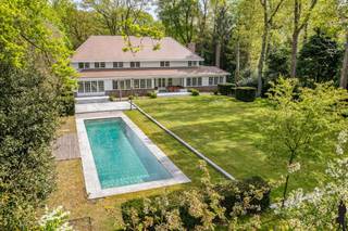 <p>Op wandelafstand van de winkels in het centrum, aan mooie laan én op een prachtig perceel grond (<strong>ca. 4.899 m²)</strong>, zeer sfeervolle en instapklare villa met achterliggende <strong>guesthouse (heden pilatesstudio + conciërgewoning) en buitenzwembad.<br /></strong><br /><strong>De gelijkvloerse verdieping: </strong></p>
<p>- Hal/entree op terracotta vloer met gastentoilet en handenwasser <br />- Een royale woonkamer (ca. 68m²) op parket met hout gestookte open haard en grote raampartijen met zicht op de tuin<br />- Een leefkeuken (ca.58m²) op terracotta vloer met gashaard, <strong>2 keukeneilanden</strong> met dubbele gootsteen, inductie kookvuur, vaatwasser en bargedeelte (4 pers.), kastenwand met 2 koelkasten+diepvries (Neff), 2 ovens en een Miele stoomoven.<br />- Een bureau/tv kamer (ca. 31m²) op parket met hout gestookte open haard en inbouwkasten<br />- Een slaapkamer (ca.18m²) op terracotategel met inloopdouche, toilet en lavabo<br />- Zij-ingang via de garage: een inpandige garage (ca.47m²) voorzien van 2 elektrische poorten, 2 uitgietbakken, en ingemaakte kasten, elektra, <br />water en verwarming. <br />- Een kelder (ca.100m²) met o.a. <strong>wijnkelder</strong>, technische ruimte, waterontharder en veel opslagruimte <br /><br /><strong><u>De eerste verdieping is op visgraatparket: <br /></u></strong>- Een nachthal op parketvloer<br />- Een <strong>royale hoofdslaapkamer (ca.27m²) met gashaard en royale dressing (ca.36m²)</strong><br />- Een ensuite marmeren hoofdbadkamer (ca.13m²) met dubbele lavabomeubel, ligbad, inloopdouche en toilet, ingemaakte kast<br />- Twee slaapkamers (ca.28m² en 17m²) <br />- Een vijfde slaapkamer (ca.13m²) met douchekamer (ca. 6m²), toilet en lavabo<br />- Een badkamer (ca.13m²) met ligbad, inloopdouche, dubbele lavabo en toilet<br /><br /><strong><u>De tweede verdieping is volledig voorzien van visgraatparket en onderliggende houtroostering:</u></strong><br />- Een zesde slaapkamer (ca.22m²) met ensuite douchekamer voorzien van inloopdouche, toilet en lavabo<br />- hobbykamer/wasplaats/berging met ingemaakte kastenwand<br /><br /><strong>Tuinhuis/guesthouse:</strong><br />Keuken voorzien van Siemens gasfornuis, gootsteen, ijskast. Douchekamer voorzien van douche, lavabo, toilet, sauna zowel gewone sauna als infraroodsauna en fitness/pilatesruimte voorzien van sporthal en balletbar. Via vaste trap naar bovenliggende verdieping waar zich de slaapkamer bevindt. <br /><br /><strong><u>Vernieuwingen:</u></strong></p>
<p>In 2010: totaalverbouwing.<br />In 2022 is het rolluik alsook de motor van het zwembad vernieuwd, alsook zijn de parketvloeren gelegd op de 1<sup>ste</sup> en 2<sup>de</sup> verdieping, keuken deels vernieuwd, OH in de keuken geplaatst, deels nieuwe terracotategel in de keuken, etc.<br />In 2023: is de elektra herkeurd<br />In 2024: is het huis volledig herschilderd (plafonds en muren) incl. de dakgoten.</p>
<p><strong><u>Algemeen:</u></strong></p>
<p>- Verwarming op gas (Remeha) d.m.v. radiatoren en vloerverwarming in het bureel, de living en deels in de keuken. Optima boiler.<br />- Alarmsysteem d.m.v. ruimtedetectie, rookmelders aangesloten op de alarminstallatie, veiligheidsdeur, domotica, waterontharder, rolluiken, vliegenramen, blokdeuren.<br />- Oprit te bereiken via automatische toegangspoort<br />Kelder bestaande uit kelder (berging) en kruipkelder, gescheiden rioleringssysteem, regenwaterput (niet in gebruik)<br />- Centrale ligging t.o.v. het centrum, openbaar vervoer, winkels en scholen</p>
<p><strong><u>Tuin:</u></strong></p>
<p>Prachtig aangelegde diepe omheinde tuin welke volledige privacy biedt.<br />Verwarmd buitenzwembad (chloor + ionisatie ) van 14m op 4m en ca. 1,5m diep. (vernieuwd rolluik en motor).<br />Diverse terrassen zowel bij het bijgebouw, als bij de villa waaronder eveneens een overdekt terras met vaste zitbank, heatstrip en muziek, zonnetent.<br />Achterliggende houtberging, tweede tuinhuis<br />Sproei-installatie</p>