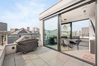 <span>Indeling</span>: <br />Gelegen in de gegeerde Pacificatiestraat te Antwerpen presenteert deze uitzonderlijke woning zich als een harmonieus samenspel van luxe, comfort en verfijnde architectuur. De totaalrenovatie werd uitgevoerd in 2019 met een eerste ingebruikname in 2022, waarbij elk detail met de grootste zorg werd afgewerkt. Hoogwaardige parketvloeren en stijlvolle gietvloeren versterken de moderne en warme uitstraling, terwijl de overvloedige lichtinval en de zuidgerichte oriëntatie de ruimtes een bijzonder aangenaam karakter geven. De woning is volledig instapklaar met een EPC-score B en conforme elektriciteit, en werd uitgerust met een geavanceerd domoticasysteem, alarmsysteem en digicode, wat veiligheid en gebruiksgemak perfect combineert. Vloerverwarming, aangevuld met radiatoren waar gewenst, zorgt voor optimaal comfort, terwijl een lift die alle niveaus verbindt, van de kelder tot het dakterras op de vierde verdieping.<br /><br />De kelderverdieping omvat een mooie wijnkelder en een praktische wasruimte. Op het gelijkvloers bevindt zich een inkomhal met toegang tot een volwaardig geïntegreerd “appartement”: een leefruimte met volledig uitgeruste keuken, een aparte slaapkamer met ensuite badkamer voorzien van inloopdouche en een koertje van 4,65 m². Deze ruimte leent zich perfect als kangoeroewoning, gastenverblijf of derde slaapkamer, en maakt integraal deel uit van de woning. De eerste verdieping herbergt een royale slaapkamer van circa 18 m² met dressing en een stijlvolle badkamer met inloopdouche. Op de tweede verdieping bevindt zich een tweede ruime slaapkamer van ongeveer 22 m² met ensuite badkamer, uitgerust met zowel bad als inloopdouche.<br /><br />De derde verdieping vormt het hart van de woning met een lichtrijke leefruimte en open keuken, die rechtstreeks toegang biedt tot een terras van 8 m². Via een trap (of met de lift) bereikt u het vierde niveau, waar twee ruime zonneterrassen verbonden worden door een unieke zomerkeuken/binnenlounge met schuifdeuren aan beide zijden. Deze harmonieuze buitenbeleving biedt een prachtig, vrij zicht over de omliggende daken en volledige privacy zonder inkijk. <br /><br />De slaapkamers zijn voorzien van maatwerk inbouwkasten en de woning ademt doorheen alle verdiepingen een gevoel van rust en verfijning.<br /><br />Daarnaast bestaat de mogelijkheid tot aankoop van twee ondergrondse binnenparkings onder de Carrefour: een afgesloten garagebox aan 65.000 euro en een autostaanplaats aan 45.000 euro, beide optioneel maar beschikbaar.<br /><br /><br /><span>Omgeving</span>:<br />De Pacificatiestraat geniet van een uiterst gegeerde ligging op het Zuid, één van de meest dynamische en stijlvolle buurten van Antwerpen. Hier woont u in een rustige straat met een residentieel karakter, terwijl u zich op wandelafstand bevindt van tal van trendy restaurants, gezellige cafés, boetieks en culturele hotspots. De nabijheid van het Museum van Schone Kunsten, de vernieuwde Scheldekaaien en verschillende parken zorgt voor een aangename combinatie van stadsleven en ontspanning.<br /><br />Dankzij de uitstekende bereikbaarheid met zowel het openbaar vervoer als belangrijke invalswegen verplaatst u zich vlot in en rond de stad. Fietsers en wandelaars genieten bovendien van de nabijgelegen groene zones en de levendige pleinen die deze buurt zo aantrekkelijk maken. De omgeving staat bekend om haar architecturale charme, brede straten en kwalitatieve residenties, wat bijdraagt aan een exclusieve en aangename woonbeleving.