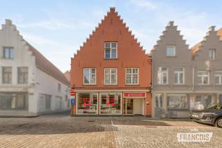 Ontdek dit veelzijdige handelspand op toplocatie in de Ezelstraat 17 te Brugge. Met een gebruiksklare handelsruimte, een achterliggend atelier van circa 40 m² en twee woongelegenheden onder één dak biedt dit eigendom tal van mogelijkheden voor ondernemers en investeerders. Dankzij de centrale ligging in de Brugse binnenstad en de combinatie van commerciële ruimte en woongelegenheden vormt dit pand een interessante opportuniteit voor wie op zoek is naar een eigen zaak met woonst of een vastgoedproject met toekomstpotentieel.<br /><br />Bij het binnenkomen ontdekt u de verzorgde handelsruimte met een mooie etalage, die volledig in orde is en onmiddellijk in gebruik kan worden genomen. Aansluitend bevinden zich een keuken en een toilet. Achteraan biedt het atelier heel wat extra mogelijkheden, bijvoorbeeld als werkplaats, opslagruimte of aanvullende professionele ruimte. Via het gelijkvloers is er bovendien toegang tot de traphal en de aparte ingang via het Zakske.<br /><br />Op de eerste verdieping bevindt zich de woonruimte boven de handelszaak, met een leefruimte, een slaapkamer, een badkamer en een voorziene ruimte voor een keuken. Op de bovenste verdieping zijn nog extra ruimtes aanwezig die, afhankelijk van de gewenste indeling, kunnen worden ingericht als één of twee bijkomende slaapkamers. De woongelegenheden dienen verder te worden aangepakt en bieden de nieuwe eigenaar de mogelijkheid om ze naar eigen smaak en wensen te renoveren en in te richten.<br /><br />Een tweede woongelegenheid beschikt over een afzonderlijke toegang via het Zakske. Deze ruimte omvat een slaapkamer, een leefruimte, een voorziene keukenruimte met aansluitende berging, een toilet en een voorziene ruimte voor een badkamer. Bovenaan bevindt zich nog een zolderruimte. Het pand biedt hierdoor verschillende indelingsmogelijkheden: van een handelspand met woonst en een afzonderlijk appartement tot een grotere woning, indien de ruimte die momenteel voor het appartement is voorzien niet afzonderlijk wordt ingericht. De renovatie en verdere optimalisatie van de woonruimtes bieden heel wat potentieel, mits rekening wordt gehouden met de eventueel vereiste vergunningen.<br /><br />Ook praktisch heeft dit eigendom heel wat te bieden. De handelsruimte beschikt over een EPC-label D en de verwarming gebeurt op aardgas via drie afzonderlijke verwarmingsketels. Bovendien is het pand vrij bij akte, waardoor u als nieuwe eigenaar meteen aan de slag kunt met uw plannen.<br /><br />Interesse? Contacteer Giovanni 0468 43 21 35 of giovanni@immofrancois.be<br /><br />