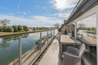 <p>Op zoek naar een high-end, instapklare penthouse op een rustige, maar centrale locatie? Dit appartement aan het water biedt een mooie combinatie van comfort en locatie.</p><p>Via de privatieve inkomhal komt u in de de zeer ruime (50m²!) en lichtrijke woonkamer met grote raampartijen en sublieme gashaard die voor extra gezelligheid zorgt in de koude wintermaanden. De volledig geïnstalleerde, open keuken met eiland is een waar genot voor zowel dagdagelijks gebruik als een leuke avond met gezelschap. Vanuit de zithoek, eetkamer en keuken geniet je op elk moment van het jaar van een open zicht op het water. Het appartement geniet van 2 ruime terrassen: 11m² aan de voorzijde met zicht op het water waar je geniet van de ochtendzon en de gehele namiddag en avond geniet je van de zon op het riant terras aan de achterzijde van meer dan 50m². Verder beschikt het appartement nog over een bergruimte en gastentoilet, alsook over twee ruime slaapkamers, elks voorzien van maatkasten. De master bedroom sluit aan op de ensuite badkamer met ruime inloopdouche, dubbele lavabo, toilet en ook hier maatkasten. Bovendien geniet het appartement van 6 privatieve zonnepanelen, wat bedraagt aan energielabel A. </p><p>Geen dagdagelijkse parkeerproblematiek dankzij de privatieve garagebox en ook opslagplaats kom je niet tekort dankzij de kelderberging.</p><p>De ligging is uitstekend: centraal in Willebroek, op wandelafstand van winkels, horeca en openbaar vervoer, en ideaal voor wandel- en fietstochten langs het water.</p><p>Stedenbouwkundige inlichtingen: aangevraagd</p>