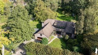 <strong>Karaktervolle villa op royaal groen domein van ca. 6.228 m² nabij het Zoerselbos<br /></strong><br /><strong>Op een prachtig groen en volledig afgesloten perceel van ca. 6.228 m², vlak bij het Zoerselbos, bevindt zich deze bijzonder ruime en uitstekend onderhouden villa. De woning werd in 2000 grondig gerenoveerd en uitgebreid en combineert royale leefruimtes met een sterke connectie met de tuin. Grote glaspartijen, veel privacy en een veelzijdige indeling zorgen voor een bijzonder aangename woonbeleving.</strong><br /><br /><strong>Gelijkvloerse verdieping</strong><br />
<ul>
<li>Ruime inkomhal met karaktervolle boogvormen, natuurstenen vloer, gastentoilet met handenwasser en afzonderlijke verstiaire;</li>
<li>Prachtige leefruimte op natuursteen met grote glaspartijen, dubbele schuiframen en een voormalige zitput, heden dichtgemaakt en geïntegreerd in de leefruimte, met een bijzonder mooi zicht op het terras en de tuin;</li>
<li>Royale leefkeuken in een vooruitgeschoven volume, waardoor het groen rondom volop beleefd wordt, met dubbele spoelbak en toestellen waaronder een AGA-fornuis, Smeg ingebouwde friteuse, Miele vaatwasser, Siemens oven en microgolfoven en een Liebherr koelkast en diepvriezer;</li>
<li>Praktische bijkeuken met ingemaakte kasten, spoelbak en toegang tot terras en tuin;</li>
<li>Twee ruime kamers op parket, ideaal als slaapkamer, bureau, speelkamer of afzonderlijke tv-kamer;</li>
<li>Inpandige garage met automatische poort;</li>
</ul>
<strong>Eerste verdieping</strong><br />
<ul>
<li>Nachthal met afzonderlijk toilet en handenwasser;</li>
<li>Hoofdslaapkamer op parket met toegang tot het dakterras en prachtig zicht over de tuin;</li>
<li>Badkamer met ligbad met jacuzzifunctie, douche, dubbele wastafel en bidet;</li>
<li>Drie bijkomende slaapkamers op parket;</li>
<li>Praktische opbergruimte onder de schuine dakvlakken;</li>
</ul>
<strong>Kelder</strong><br />
<ul>
<li>Kelderruimte met ingemaakte kasten met geïntegreerde koel- en diepvriesvoorzieningen;</li>
<li>Bijkomende bergmogelijkheden;</li>
</ul>
<strong>Tuin en buitenruimte</strong><br />
<ul>
<li>Uitzonderlijk ruime en prachtig aangelegde tuin met volwassen bomenbestand;</li>
<li>Uitgestrekte gazonzones, sierbomen, hagen en sfeervolle vijver;</li>
<li>Ruim terras en gedeeltelijk overdekt terras aansluitend op de leefruimtes;</li>
<li>Diepe zichtlijnen en een bijzonder gevoel van rust en privacy;</li>
<li>Chalet/gastenverblijf met badkamer, toilet, kitchenette en afzonderlijke recente verwarmingsketel;</li>
<li>Serre en tuinhuis met bijkomende opbergruimte en 3 carports;</li>
<li>Volledig omheind en afgesloten domein met automatische toegangspoort;</li>
<li>Robotmaaier</li>
</ul>
<strong>Algemeen</strong><br />
<ul>
<li>Woning grondig gerenoveerd en uitgebreid in 2000;</li>
<li>Elektrische installatie vernieuwd in 2004 (en conform);</li>
<li>Wateronthardingsinstallatie JUDO;</li>
<li>Verwarming op aardgas (deels) via vloerverwarming;</li>
<li>Parketvloeren recent opnieuw opgeschuurd;</li>
<li>Interieur en buitenschrijnwerk recent volledig opnieuw geschilderd;</li>
<li>Zeer verzorgde en uitstekend onderhouden eigendom;</li>
<li>Videofonie;</li>
<li>Veelzijdige indeling met mogelijkheden voor thuiswerk, hobby, gasten of bijkomende slaapkamers;</li>
<li>Bijzonder veel privacy dankzij de omvang en groene omkadering van het perceel;</li>
</ul>
<strong>Inclusief naastgelegen perceel</strong><br />Naast het hoofdeigendom bevindt zich een afzonderlijk perceel van ca. 1.520 m², inbegrepen in de vraagprijs. Op dit perceel bevindt zich momenteel een achterliggend atelier met carport.