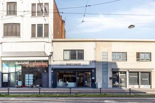 <p><span>Op een commerciële locatie aan de Bredabaan in Merksem bevindt zich dit ruime handelspand van ca. <strong>294 m²</strong>, momenteel ingericht als bakkerij met tearoom. Het pand wordt verkocht <strong>inclusief de aanwezige professionele bakkerij-uitrusting</strong> en biedt zo een uitstekende opportuniteit voor wie een volledig ingerichte zaak wil overnemen.</span></p><p><span>Het gelijkvloers bestaat uit een recent gerenoveerde winkelruimte met ruime toonbank, glazen vitrines en een verzorgde afwerking. Aansluitend bevindt zich de tearoom met zitplaatsen en een bijkomend verkoopgedeelte met koelvitrines.</span></p><p><span>Achteraan bevindt zich het volledig uitgeruste bakkerijatelier met onder meer dekovens, industriële deegmengers, rijskasten, inox werkbladen, professionele vaatwasser en ruime opslagmogelijkheden. Daarnaast zijn er afzonderlijke toiletten voor dames en heren.</span></p><p><span>Via een interne trap bereik je de bovenverdieping, die bijkomende ruimte biedt voor opslag of andere invullingen.</span></p><p><span>Het pand beschikt over een vernieuwde Vaillant condensatieketel. Het platte dak en de gevels bieden nog mogelijkheden om de energieprestaties verder te verbeteren.</span></p><p><span>Dankzij de ruime oppervlakte, commerciële ligging en volledige inrichting is dit pand ideaal voor een bakker die onmiddellijk van start wil gaan, maar eveneens interessant voor andere handels- of horecaconcepten.</span></p><p><span><strong>Bijzonderheden:</strong></span><br /><span>294 m² | Professionele bakkerij-uitrusting inbegrepen | Tearoom | EPC E | Vaillant condensatieketel | Plat dak | Bestemming horeca | EPC, asbestattest en elektrisch keuringsverslag beschikbaar | Renovatieverplichting van toepassing.</span></p>