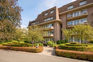 Dit ruime gelijkvloerse appartement biedt een aangename combinatie van leefruimte, lichtinval en zicht op het omliggende groen. De parketvloeren, grote raampartijen en het ruime terras zorgen voor een open en comfortabel geheel.<br /><br />Via de inkomhal op tegelvloer betreedt u het appartement. Hier bevinden zich een ingemaakte vestiaire en een afzonderlijk gastentoilet met handenwasser. <br /><br />Verder komt u in de ruime open leefruimte op parket, met een zithoek en eetkamer. De grote raampartijen zorgen voor veel natuurlijk licht en geven uit op het park. Vanuit de leefruimte is er rechtstreeks toegang tot het terras, dat voldoende plaats biedt voor zowel een eettafel als een zithoek.<br /><br />De keuken is volledig uitgerust en voorzien van alle nodige toestellen. Ook van hieruit is er rechtstreekse toegang tot het terras. Aansluitend bevindt zich een praktische berging/wasplaats.<br /><br />Het appartement beschikt over 2 slaapkamers en 2 badkamers. De eerste slaapkamer is afgewerkt met parket en beschikt over een ingemaakte kast en een eigen balkon aan de noordzijde. Daarnaast bevindt zich een badkamer met douche, lavabo en toilet.<br /><br />De hoofdslaapkamer is eveneens afgewerkt met parket en beschikt over een eigen balkon en een ruime inloopdressing met ingemaakte kasten. De tweede badkamer is voorzien van een ligbad, douche, dubbele wastafel en toilet.<br /><br />Een ruim gelijkvloers appartement met twee slaapkamers, twee badkamers, meerdere buitenruimtes en een aangenaam zicht op het park.<br /><br />De verkoop richt zich in eerste instantie tot kopers die het appartement als opbrengsteigendom wensen aan te kopen, aangezien de huidige eigenaar de woning nog gedurende circa drie à vier jaar wenst te blijven bewonen.<br /><br />Het prachtige parkdomein 'De Wilaard' wordt gekenmerkt door zijn unieke stilte, rust, vijvers en prachtige bomenbestand. Het domein van ca 12ha is altijd perfect onderhouden en straalt een adembenemende schoonheid uit, het ganse jaar door. Desondanks zijn rustige ligging geniet het domein toch een uitstekende bereikbaarheid met het centrum en station van Kapellen op slechts 5 minuten wandelen. Ook alle voorzieningen, invalswegen en openbaar vervoer bevinden zich op een boogscheut.<br />Een buitengewone kans om te wonen in een luxueus appartement in de uiterste rust.