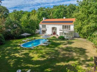 <p>Zoekt u het ultieme vakantiegevoel zonder uw huis te verlaten? Dan is deze villa de perfecte woning voor u. Deze luxe, moderne en zeer lichte villa bevindt zich in de groene, residentiële Bellemond wijk op een toplocatie te ’s Gravenwezel. Hier geniet u van volledige privacy in een prachtige zuidwest-georiënteerde tuin met een verwarmd zwembad. De villa is ideaal gelegen nabij scholen, openbaar vervoer en winkels, en ligt in een van de meest prestigieuze wijken van ’s Gravenwezel.</p>
<p>Deze architectenwoning, ontworpen door de gerenommeerde architect John Bontinck, is gebouwd met hoogwaardige materialen. De visie van de architect om de tuin sterk bij de woning te betrekken, is werkelijk verbluffend geslaagd. Bij binnenkomst wordt u meteen gecharmeerd door het vakantiegevoel dat de villa uitstraalt. Een prachtige doorkijk naar de tuin en het zwembad verwelkomt u direct.<br /><br />INDELING<br /><br /><strong>Gelijkvloers:<br /></strong>Bij binnenkomst wordt u meteen gecharmeerd door het vakantiegevoel dat de villa uitstraalt. Een prachtige doorkijk naar de tuin en het zwembad verwelkomt u direct. <br />U treedt de villa binnen via een inkomhal met een apart gastentoilet en een ruime vestiaire. Een dubbele glazen deur biedt toegang tot de riante en lichte woonkamer met een doorlopend raam tot de verdieping. De leefruimte, verdeeld in zithoek, salon en eetkamer, is voorzien van een eiken parketvloer en een prachtig open haard. De ruimtes vloeien mooi in elkaar over en zijn in direct contact via grote deurramen met het zuidwest-georiënteerde terras, de tuin en het zwembad.<br /><br />Aansluitend aan de leefruimte vindt u de volledig geïnstalleerde keuken met een kookeiland, ontbijthoek, tal van opbergkasten en moderne toestellen, waaronder een Amerikaanse koelkast. Door kamerhoge raampartijen rondom de keuken wordt deze ruimte overspoeld met natuurlijk licht en biedt het een prachtig uitzicht op de tuin en het zwembad.<br /><br />Een praktische douchekamer met toegang naar buiten is ideaal na een zwembeurt in het zwembad.<br /><br />Een mooie houten trap leidt naar de eerste verdieping, waar een impressionante vide extra licht en uitzicht biedt vanuit de verdieping op de prachtige tuin.<br /><br /><strong>1e Verdieping:<br /></strong>Op de 1e verdieping vindt u de mastersuite met dressing en badkamer – met ligbad, dubbele lavabo en toilet. De 2e slaapkamer (ca. 31m²) op parket met ingemaakte kasten geeft uit op een prachtig terras. De 2e (ca. 20m²) en 4e slaapkamers (ca. 18m²) delen de 2e badkamer met ligbad, lavabo en toilet. Verder is er nog een handige berging, ideaal voor een linnenkast of een extra douchekamer.<br /><br /><strong>Tuin en Zwembad<br /></strong>Geniet volop van de zonnige tuin in volledige privacy zonder enige inkijk. De tuin is aangelegd met verschillende terrassen, een verwarmd zwembad en een tuinhuis. Deze buitenruimte biedt de perfecte setting voor ontspanning, zomerse barbecues en gezellige avonden.<br /><br />Een inpandige garage biedt ruimte voor 2 wagens en heeft een automatische toegangspoort. Daarnaast is er een ruime oprit met plaats voor meerdere wagens, wat extra gemak en parkeerruimte biedt voor u en uw gasten.<br /><br />Kortom, deze villa is een waar paradijs voor wie houdt van een luxe levensstijl met een vleugje vakantie. De ruime indeling en grote ramen zorgen voor een lichte en luchtige sfeer. Mis deze unieke kans niet om in een van de meest gewilde wijken van ’s Gravenwezel te wonen.</p>
<p></p>
<p>BIJZONDERHEDEN:<br />+ Architect John Bontinck<br />+ Nieuw gietvloeren op verschillende ruimtes<br />+ Vloerverwarming <br />+ 15 zonnepanelen (2024)<br />+ Gunstig EPC: 164kWh/m²<br />+ Vloerverwarming op GLV<br />+ Asbestvrij.<br />+ Bose audio-installatie in alle ruimtes, voor optimale geluidservaring.<br /><br />Voor meer informatie of een bezoek aan deze gezellige woning, neem gerust contact op met Sigalit via Sigalit@reds.be of op 0475668474</p>