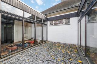 Vlakbij het Groenhovebos te Torhout treffen we deze knappe architectenwoning aan. Een bewoonbare oppervlakte van + 350 m² die zich uitermate leent voor het uitvoeren van een vrij beroep en een perceel van + 5.000 m², mits enkele opfrissingswerken is maak je van deze eigendom terug een gedroomde eigendom.<br />Indeling:<br />Riante inkomhal met zicht op de binnentuin en toegang naar het bureau met wachtruimte enerzijds en naar de sfeervolle woonkamer anderzijds. De ruime woonkamer bevat een eetplaats en het salon, boven dit salon is nog een polyvalente ruimte (bibliotheek, bureau,,...). Vanuit de woonkamer heeft u zicht op de tuin met vijver en is er toegang tot het zonnige terras. <br />Aparte keuken voorzien van alle comfort en toegang naar de kelder. De burelen zijn toegankelijk vanuit de inkomhal (met apart toilet en lavabo). <br />De slaapkamers zijn toegankelijk via de nachthal, vertrekkend vanuit de woonkamer. 3 Slaapkamers waarvan 2 met ingemaakte kasten en lavabo. De 4de kamer doet momenteel dienst als wasplaats/technische ruimte. Badkamer met dubbele lavabo, toilet en inloopdouche.<br />Aparte garage voor 2 wagens en ruime parking.<br />Grote onderhoudsvriendelijke tuin rondom de woning met vijver ter hoogte van het terras. De vijver werd voorzien van alle technieken om dienst te doen als koi-vijver.<br /><br />Bouwtechnisch: CV op stookolie - 42 Zonnepanelen met 2 afzonderlijke omvormers en een zonneboiler – Houten ramen met dubbele beglazing – droge kelder – Conforme elektriciteit