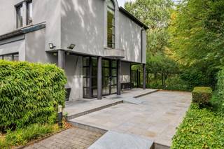 <p><span>Ruime op te frissen woning met 4 slaapkamers, wellness, dubbele garage en tal van mogelijkheden!</span></p><p><span> </span></p><p><span>Deze bijzonder ruime woning combineert een royale bewoonbare oppervlakte met tal van mogelijkheden en een uitstekende bereikbaarheid. De woning is momenteel ingericht als</span></p><p><span>kantoorruimte, maar beschikt over een volwaardige residentiële indeling en kan opnieuw worden ingericht tot een comfortabele gezinswoning.</span></p><p><span> </span></p><p><span>Op het gelijkvloers bevindt zich een ruime inkomhal met gastentoilet. Aan de linkerzijde vinden we een afzonderlijke bureauruimte, ideaal als thuiskantoor of praktijkruimte.</span></p><p><span>De royale leefruimte biedt plaats aan zowel een ruime eetplaats als een aparte, gezellige zithoek met gashaard alsook een TV-ruimte.</span></p><p><span>Grote raampartijen zorgen voor veel natuurlijk licht en zijn op het gelijkvloers voorzien van zonneluifels. De woning is hoofdzakelijk afgewerkt met tegelvloeren en beschikt over in de vloer geïntegreerde convectoren.</span></p><p><span>De zeer ruime keuken biedt veel werk- en bergruimte en geeft via de achterdeur rechtstreeks toegang tot het terras en de tuin. Aansluitend bevinden zich nog een praktische berging en bijkeuken.</span></p><p><span>Een absolute troef is de grote polyvalente ruimte, momenteel ingericht met een bar. Onder de huidige vloer bevindt zich het oorspronkelijke binnenzwembad. De vloerconstructie kan opnieuw worden verwijderd, waardoor het zwembad opnieuw in gebruik kan worden genomen en hier een prachtige ontspanningsruimte kan worden gecreëerd. Aansluitend bevindt zich een aparte wellnessruimte met stoomcabine en sanitair.</span></p><p><span> </span></p><p><span>Op de verdieping bevinden zich vier volwaardige slaapkamers. De master bedroom beschikt over ingebouwde kasten. Eén van de slaapkamers heeft een eigen douchekamer. Daarnaast is er een ruime badkamer met ligbad, douche, lavabo en toilet. Ook de verdieping is hoofdzakelijk voorzien van tegelvloeren.</span></p><p><span> </span></p><p><span>Ook aan praktische ruimte is er geen gebrek. De woning beschikt over een zeer ruime, volledig betegelde kelder en een dubbele inpandige garage, rechtstreeks bereikbaar via de oprit.</span></p><p><span> </span></p><p><span>Voor extra comfort is zowel op het gelijkvloers als op de verdieping airconditioning aanwezig. Daarnaast beschikt de woning over een alarmsysteem, een gashaard en werd de verwarmingsinstallatie ongeveer vier jaar geleden vernieuwd.</span></p><p><span>Ook energetisch is er een belangrijke troef: de woning heeft een EPC-score van C, waardoor er geen renovatieverplichting van toepassing is.</span></p><p><span> </span></p><p><span>Buiten valt meteen de uitzonderlijk ruime parking aan de voorzijde op, met plaats voor meerdere wagens. Achteraan geniet u van een mooi terras en een ruime, groene tuin. De achterliggende groene omgeving zorgt bovendien voor een aangenaam en open karakter.</span></p><p><span> </span></p><p><span>De woning kan op bepaalde punten naar eigen smaak worden opgefrist, maar biedt dankzij haar uitzonderlijke ruimtes, vier slaapkamers, binnenzwembad en wellnessmogelijkheden, dubbele garage en ruime buitenomgeving bijzonder veel potentieel. Ook voor wie wonen en werken wil combineren, biedt dit pand interessante mogelijkheden.</span></p><p><span> </span></p><p><span>Troeven:</span></p><p><span> - EPC-score C  geen renovatieverplichting</span></p><p><span> - 4 slaapkamers</span></p><p><span> - Zeer ruime leefruimtes</span></p><p><span> - Grote keuken met aansluitende berging en bijkeuken</span></p><p><span> - Binnenzwembad aanwezig onder de huidige vloer</span></p><p><span> - Wellnessruimte met stoomcabine</span></p><p><span> - Airconditioning op gelijkvloers en verdieping</span></p><p><span>- Gashaard</span></p><p><span> - Vloerconvectoren</span></p><p><span>- Verwarmingsinstallatie ca. 4 jaar geleden vernieuwd</span></p><p><span>- Grote, volledig betegelde kelder</span></p><p><span> - Dubbele inpandige garage</span></p><p><span>- Uitzonderlijk ruime parking vooraan</span></p><p><span> - Mooi terras en groene tuin</span></p><p><span>- Achterliggende groene omgeving</span></p><p><span>- Alarmsysteem</span></p><p><span> - Interessant voor combinatie wonen en werken</span></p><p><span> - Goede bereikbaarheid</span></p>