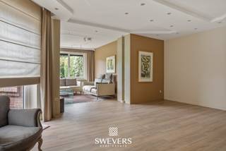 Voor meer info en foto’s, surf naar www.swevers.be – Op een strategische locatie in Tessenderlo-Ham ontdek je deze uitzonderlijk ruime rijwoning met een bewoonbare oppervlakte van 365 m² op een perceel van 8a 75ca. De woning werd oorspronkelijk gebouwd in 1948 maar onderging meerdere renovaties: een nieuw dak (1989), vernieuwde ramen (2015) en een moderne keuken (2018). De gelijkvloerse verdieping biedt o.a. een leefruimte van 50 m², aparte eetkamer, ruime keuken (28,6 m²), badkamer, wasplaats en een garage van 40 m². Daarnaast zijn er praktijkruimtes met aparte ingang, ideaal voor zelfstandigen. Op de eerste verdieping vind je drie grote slaapkamers, een tweede badkamer, apart toilet en een extra kamer die als dressing of bureau kan dienen. De zolderverdieping is volledig ingericht als extra woongedeelte met woonkamer, aansluitingen voor een keuken, slaapkamer of polyvalente ruimte van 55 m², vijfde slaapkamer, zesde slaapkamer of polyvalente ruimte en balkon. Dankzij de zonnepanelen en zonneboiler, gunstige oriëntatie en centrale ligging nabij winkels, scholen en openbaar vervoer, is dit een ideale woning voor grote gezinnen of wie wonen en werken wil combineren. Voor meer informatie, bel 011 255 155. Bron bewoonbare oppervlakte: EPC – verslag.