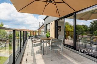 ***PROMO PROMO KOOPT U HET APPARTEMENT TIJDENS ONZE DISCOVERYS DAYS OP ZATERDAG 10/10, KRIJGT U DE AUTOSTAANPLAAT ER GRATIS BIJ!*** Ontdek dit uitzonderlijke penthouse van 121 m² in de recente Residentie High Five te Vilvoorde gebouwd in 2025, waar hedendaagse architectuur, luxueuze afwerking en baanbrekende energieprestaties perfect samenkomen. Dankzij de volledige zuidoriëntatie, grote raampartijen en het indrukwekkende panoramische terras geniet u de hele dag van een overvloed aan natuurlijk licht en een prachtig groen uitzicht.<br /><br />De royale leefruimte met stijlvolle open keuken vormt het hart van de woning. De keuken is uitgerust met hoogwaardige toestellen en een elegant kookeiland, ideaal voor wie houdt van koken en gezellig tafelen. Via de grote schuiframen loopt u rechtstreeks naar het ruime zonneterras, een heerlijke plek om in alle rust te ontspannen.<br /><br />De ruime slaapkamer beschikt eveneens over een rechtstreekse toegang tot het terras en wordt aangevuld met een op maat gemaakte dressing. Daarnaast is er een tweede polyvalente kamer die perfect dienst kan doen als slaapkamer, bureau of hobbyruimte. Verder beschikt het appartement over een luxueuze douchekamer, een afzonderlijk toilet, een volledig ingerichte wasruimte, een vestiaire met design glazen deuren, een gemeenschappelijke fietsenberging en een privatieve buitenberging.<br /><br />Dit penthouse behoort tot de absolute top op vlak van energiezuinigheid. Met een EPC A, een uitzonderlijk E-peil E3, een warmtepomp, zonnepanelen, vloerverwarming op lage temperatuur, actieve koeling en hoogwaardige thermische en akoestische isolatie geniet u van maximaal wooncomfort én bijzonder lage energiekosten. Dankzij de eigen energieproductie bedraagt het geschatte elektriciteitsverbruik slechts ongeveer €20 per maand.<br /><br />Bij het appartement hoort een extra brede, beveiligde autostaanplaats met laadpunt voor een elektrische wagen, aan te kopen voor €30.000. De gemeenschappelijke kosten bedragen slechts €85 per maand, inclusief syndicus, gebouwverzekering en onderhoud.<br /><br />Een bijkomende troef is dat dit appartement verkocht wordt onder het gunstige nieuwbouwregime, zonder 21% btw, met bovendien de mogelijkheid om onder bepaalde voorwaarden te genieten van het verlaagde btw-tarief van 2%. Daarnaast profiteert u nog van de resterende 10-jarige structurele garantie van de projectontwikkelaar.