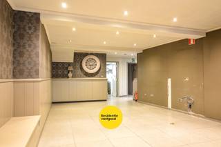 Deze ruime handelswoning in het centrum van Aartrijke combineert wonen en werken. Het handelspand beschikt over een volledig ingerichte keuken met aansluitend een ruime frigocel, ideaal voor horeca- of voedingsactiviteiten. Voor een vlotte logistieke werking is er een aparte doorgang voor leveranciers voorzien, zodat leveringen efficiënt kunnen gebeuren zonder de klantenruimte te storen. Daarnaast zijn er aparte toiletten voor de zaak.<br />Aan de handelsruimte bevindt zich een aangenaam overdekt terras met luifel, perfect om klanten in alle seizoenen een gezellige buitenruimte te bieden.<br /><br />Het woongedeelte bevindt zich eveneens op het gelijkvloers en biedt een comfortabele living met veel lichtinval. Op deze verdieping bevindt zich ook de slaapkamer evenals een zonnig binnenterras waar u in alle privacy kan genieten. Op de eerste verdieping vindt u de badkamer en twee bijkomende slaapkamers. <br /><br />Kortom, een veelzijdige handelswoning met praktische indeling en aangename woonruimtes.<br />EPC: energielabel C (Vg, Gmo, Wg, Gvkr, Gvv) Ref. OU28666<br /><br />Neem voorsprong met een vrijblijvende en gratis schatting van uw eigendom via:<br />www.residentievastgoed.be/gratisonlineschatten