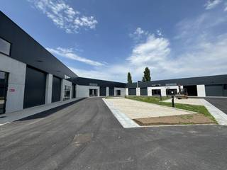 Bedrijfsverzamelgebouw De Rick biedt moderne werkruimte op de voormalige Sega-Meat site aan de Ricksteenweg 23B. Het park omvat 14 casco KMO-units, waarvan er nog 3 beschikbaar zijn.Technische kenmerkenHet gebouw is opgetrokken in duurzame materialen. De draagstructuur bestaat uit stalen spanten en kolommen of betonnen elementen. De gevels combineren betonpanelen van 27 cm met geïsoleerde metalen sandwichpanelen. De vloer is een gewapende betonplaat van 15 cm met 4 cm XPS-isolatie. Het dak in steeldeck is voorzien van minstens 100 mm PIR-isolatie en een lichtstraat voor natuurlijke lichtinval. Vrije hoogte is 7 meter.Uitrusting per unitUnits worden casco geleverd voor eigen inrichting. Elke unit heeft een elektrische sectionaalpoort in antraciet met afstandsbediening en een aluminium loopdeur met bovenlicht. Nutsvoorzieningen omvatten water en elektriciteit (3f400V-40A). Er is een wachtbuis voor data en telefonie.Duurzaamheid en waterElke unit heeft zonnepanelen (+/- 3.600Wp) op het dak. Er is een eigen regenwaterput van 5.000L met aanzuigleiding.Veiligheid en aanlegDe units vallen onder brandklasse C. Er is een brandmeldcentrale met rookdetectoren en een RWA-rookluik aanwezig. De rijweg is van asfalt; parkings en opritten bestaan uit drainerende betonklinkers. Gemeenschappelijke delen omvatten een brievenbusgeheel en een fietsenstalling voor circa 20 fietsen
