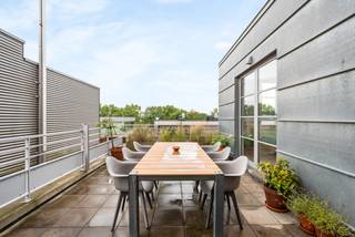 Op een toplocatie aan de Nieuwe Kaai in Turnhout bevindt zich deze karaktervolle fabrieksloft van ca. 102 m², gelegen op de 5de verdieping van ‘Anco B2’, het voormalige hoofdgebouw van de bekende Anco-pastafabriek. Het gebouw dateert uit de periode 1950-1960 en werd met respect voor zijn industriële karakter gerenoveerd, waarbij de typische architectuur en authentieke uitstraling maximaal behouden zijn gebleven.<br /><br />De loft onderscheidt zich door zijn hoge plafonds, aangename lichtinval en prachtige vergezichten. Daarnaast beschikt het appartement over maar liefst twee terrassen, waaronder een ruim zuidgericht terras, waar je heerlijk van de zon en het uitzicht kunt genieten.<br /><br />De indeling omvat een ruime en lichtrijke woonkamer met parketvloer, een aangename leefkeuken uitgerust met een vaatwasser, inductiekookplaat, koelkast en combi-oven, twee slaapkamers en een ruime badkamer met ligbad/ douche, dubbele lavabo in meubel en een toilet.<br /><br />Bijzonderheden:<br />*2 terrassen, waaronder een ruim zuidgericht terras<br />*Hoge plafonds en veel natuurlijke lichtinval<br />*Parketvloer in de woonkamer<br />*Lift aanwezig<br />*EPC-label B<br />*Gelegen op een toplocatie aan de Nieuwe Kaai<br />*Karaktervolle industriële architectuur met behoud van de authentieke uitstraling