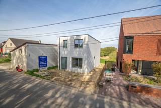 In het groene Pepingen wordt deze instapklare en energiezuinige woning gebouwd op een terrein met natuurlijke helling. Het resultaat? Een verhoogd terras op palen met een indrukwekkend zicht over de omliggende velden – elke dag genieten van rust en ruimte.
Deze compacte, slimme gezinswoning heeft alles in huis: drie slaapkamers, een open leefruimte met veel lichtinval, een volledig uitgeruste keuken van ATAG, een moderne badkamer met inloopdouche en handdoekdroger, een praktische wasplaats en twee toiletten. Voor de deur zijn twee privéparkeerplaatsen voorzien.
Als BEN-woning (bijna-energieneutraal) is ze uitgerust met toptechniek:
– Hoogrendementsglas (U-waarde 1.0)
– Ventilatiesysteem D
– Warmtepompboiler van 200 liter
– 13 zonnepanelen van 410 Wp met omvormer
– Warmtepomp lucht-lucht 3,5 kW in living en keuken
– Twee extra lucht-lucht warmtepompen boven (1 in master bedroom, 1 in nachthal voor de kinderkamers)
Dit zorgt voor een aangenaam binnenklimaat in zomer én winter, met een EPC-score A als gevolg. Dankzij de doordachte indeling en energiezuinige uitrusting is dit de ideale gezinswoning, eerste woning of investering in de toekomst.
De woning wordt volledig afgewerkt onder het btw-stelsel (21%). De getoonde foto zijn van een eerder gerealiseerde woning.